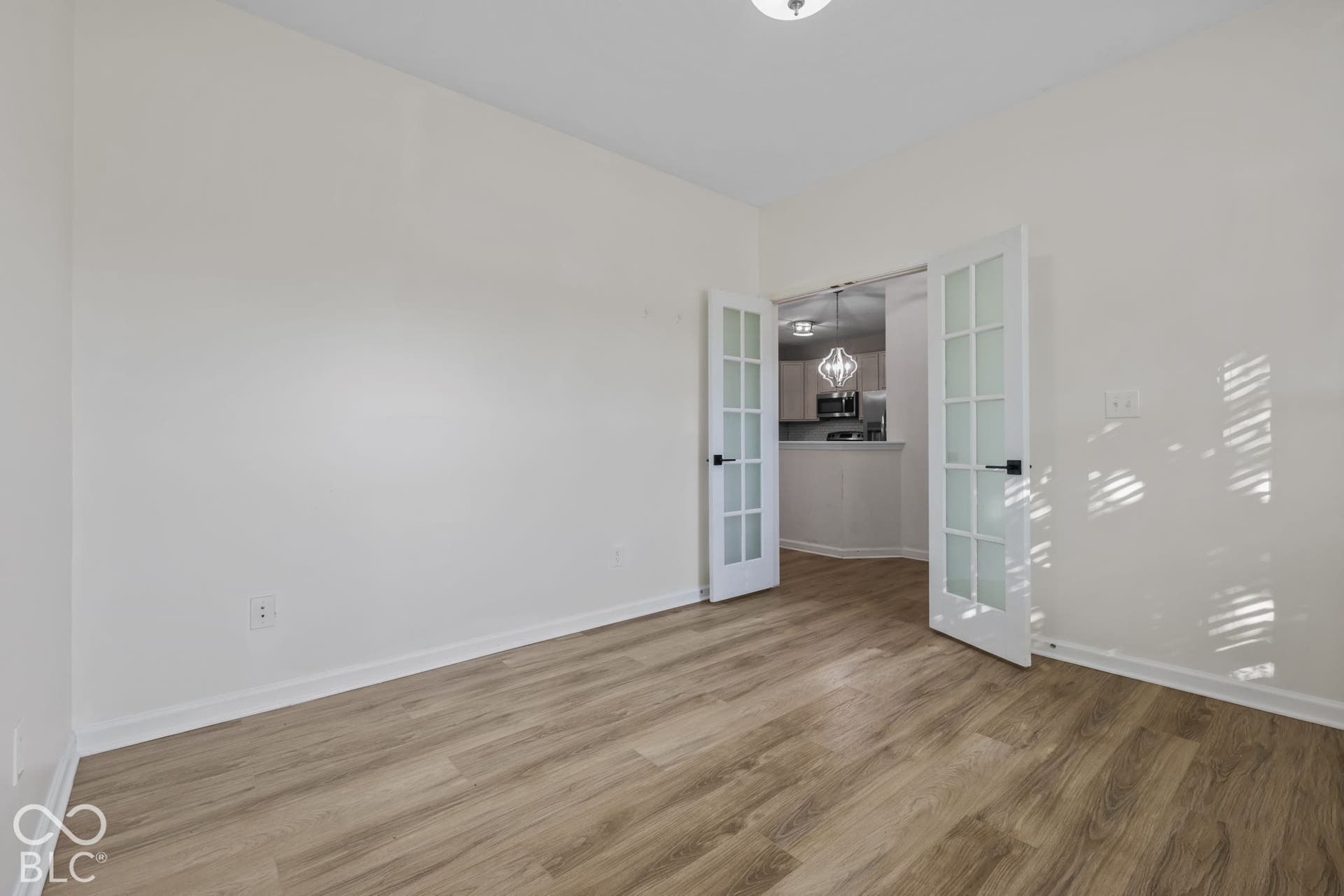 Room featuring wood-finish flooring, white walls, and French doors with glass panes and matte black hardware