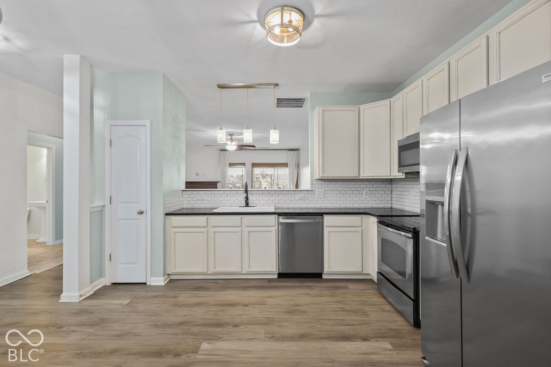Kitchen featuring shaker-style cabinetry, dark stone countertops, white subway tile backsplash, stainless steel appliances, and wood-finish flooring