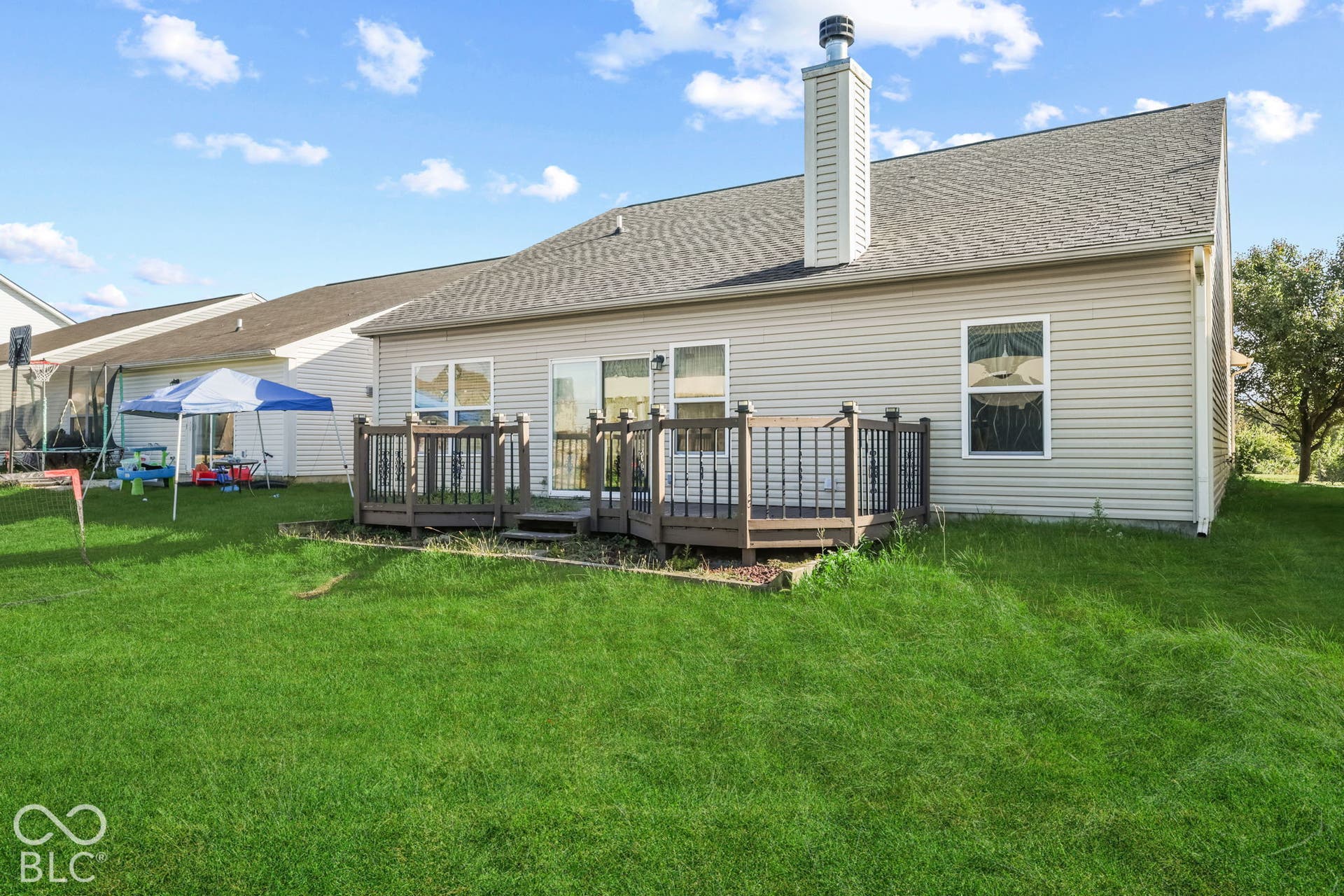 Rear exterior featuring horizontal vinyl siding, shingle roof, chimney, and a multi-level wood deck with integrated railings