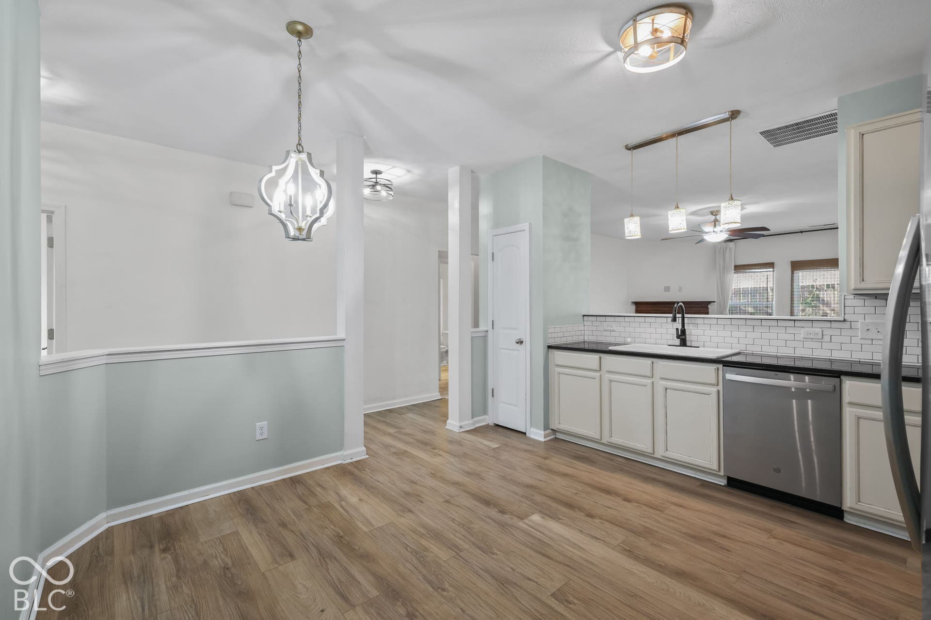 Kitchen featuring light-finish cabinetry, subway tile backsplash, stainless steel dishwasher, wood-finish flooring, and decorative pendant lighting
