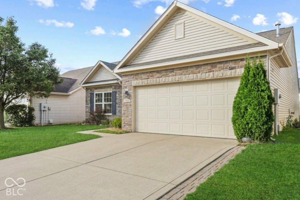 Exterior featuring horizontal siding, stone veneer accents, an attached two-car garage, and concrete driveway
