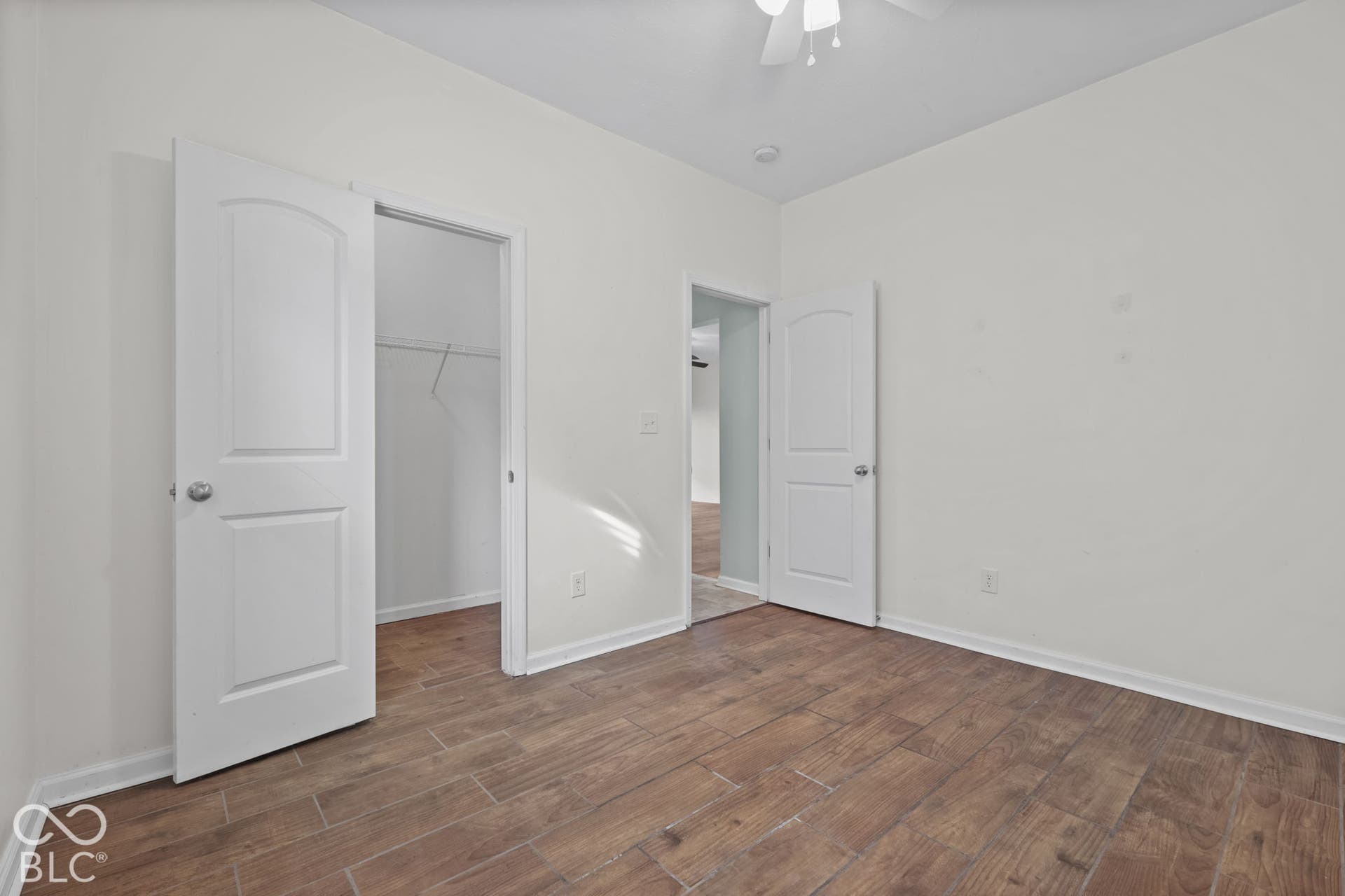 Interior room featuring wood-finish flooring, two-panel interior doors, a reach-in closet, and a ceiling-mounted light fixture