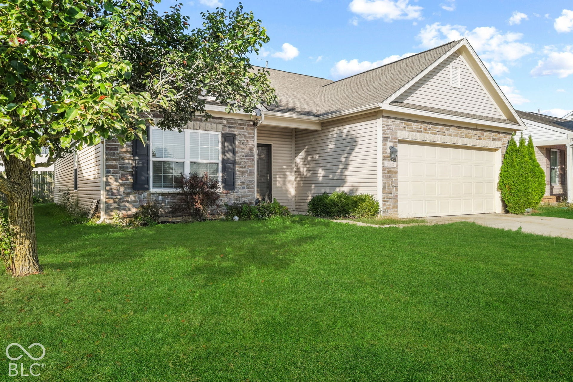 Single-story exterior featuring stone veneer and horizontal siding, multi-pane windows with shutters, and an attached two-car garage