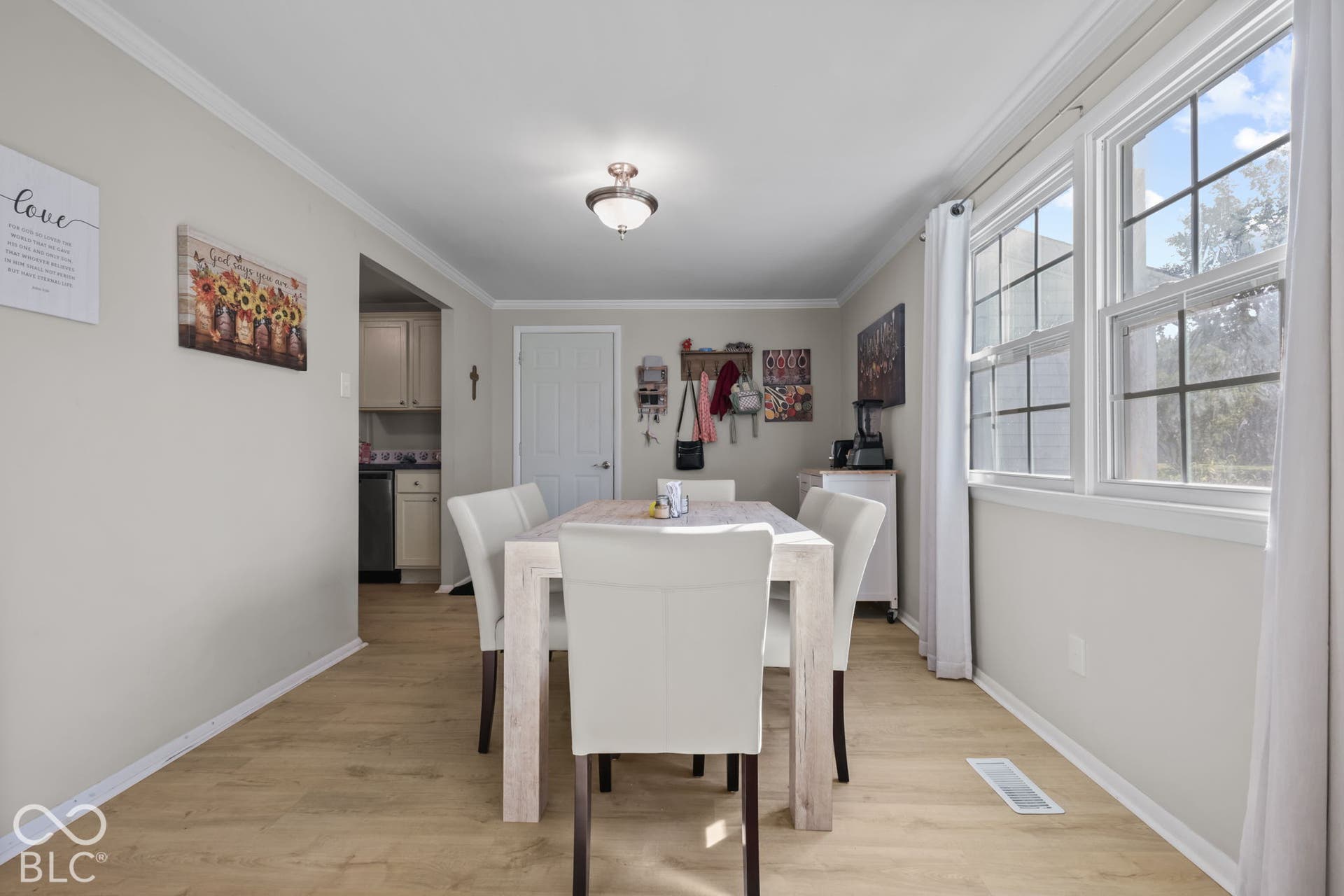 Wood-finish flooring, neutral wall tones, multi-pane windows, and a flush-mount light fixture
