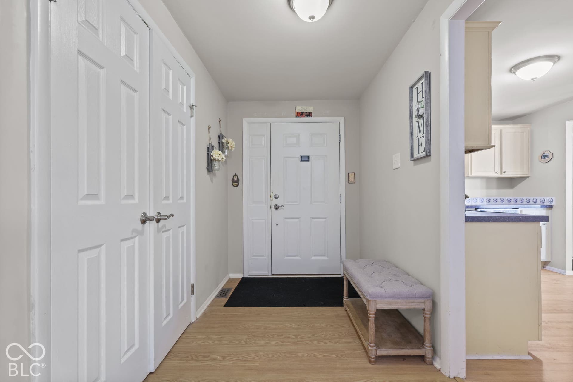 Entryway featuring wood-finish flooring, a six-panel front door with sidelights, and double-door closet storage with brushed nickel hardware