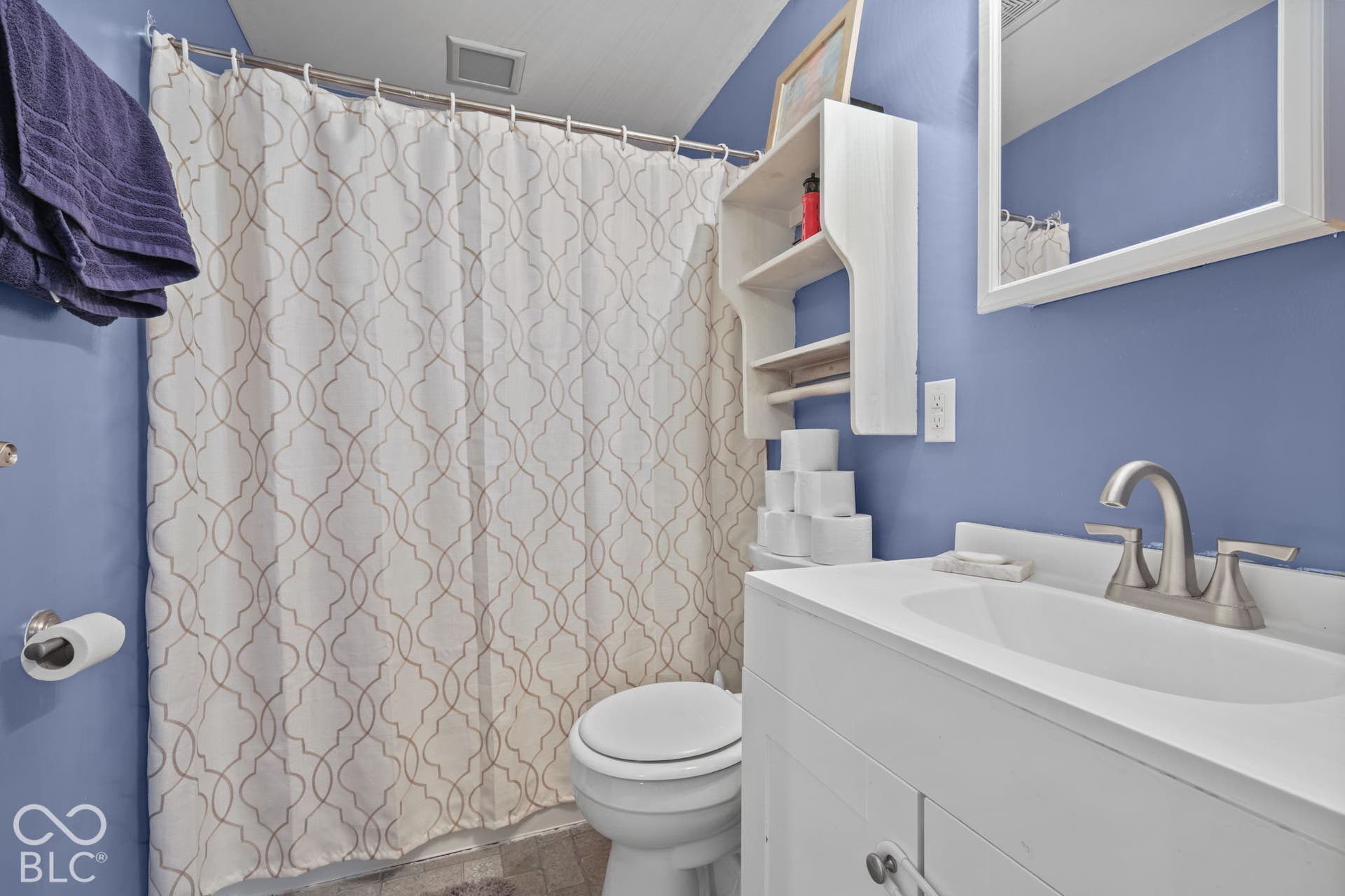 Bathroom featuring a white vanity with an integrated sink, brushed-nickel widespread faucet, built-in wall shelving, and a wall-mounted medicine cabinet