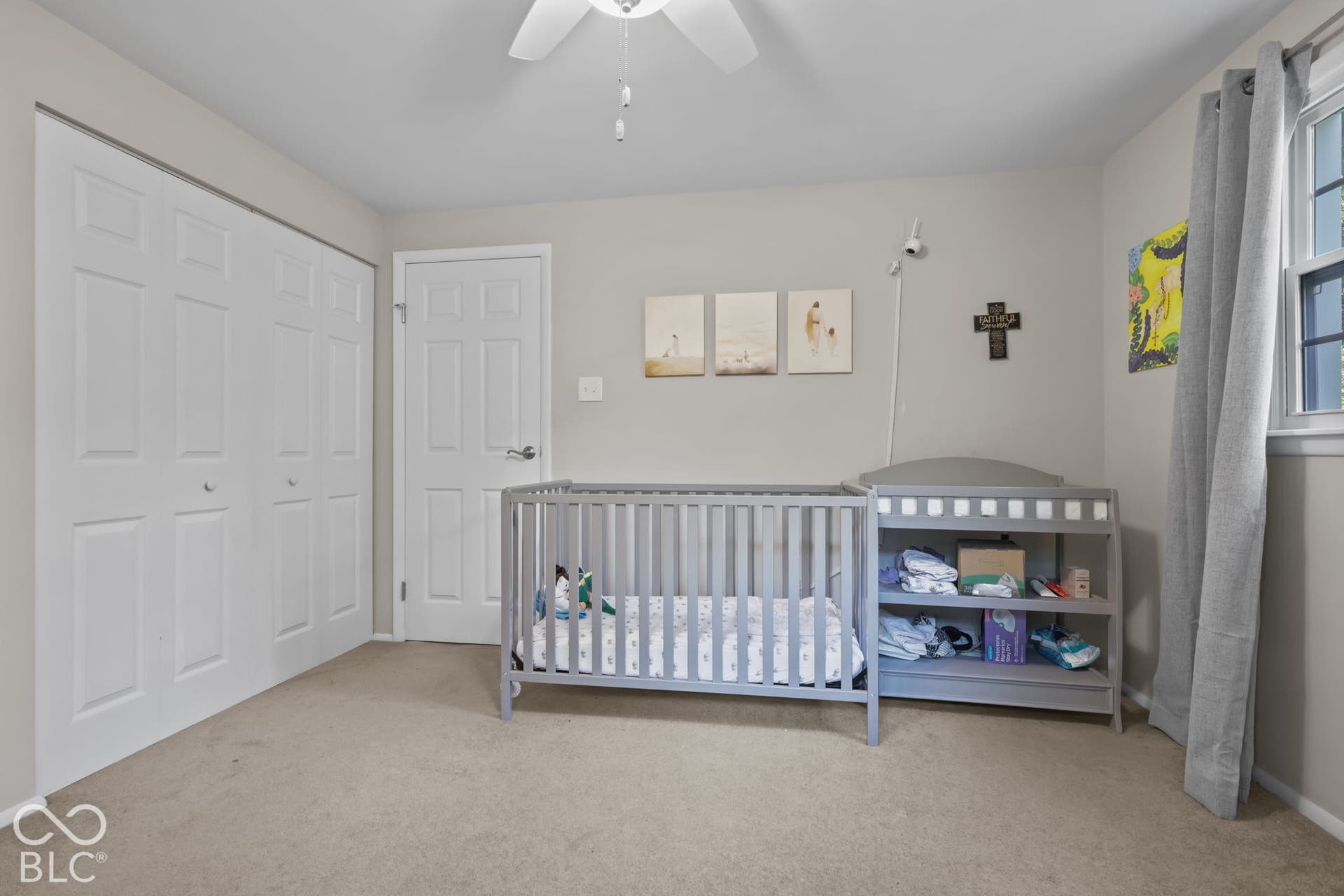 Room featuring neutral-toned carpeting, a ceiling fan with integrated lighting, dual-panel closet doors, and a single-panel interior door
