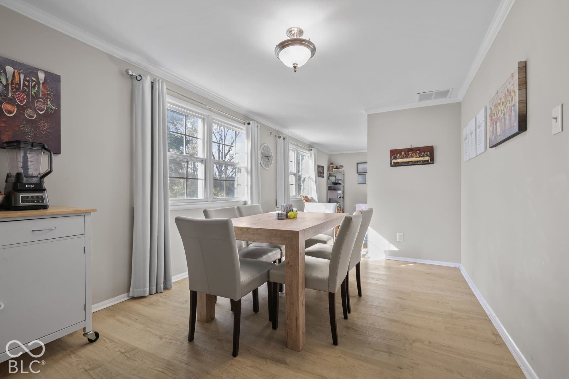 Neutral-toned interior space featuring wood-finish flooring, multi-pane windows, and a flush-mount ceiling light fixture