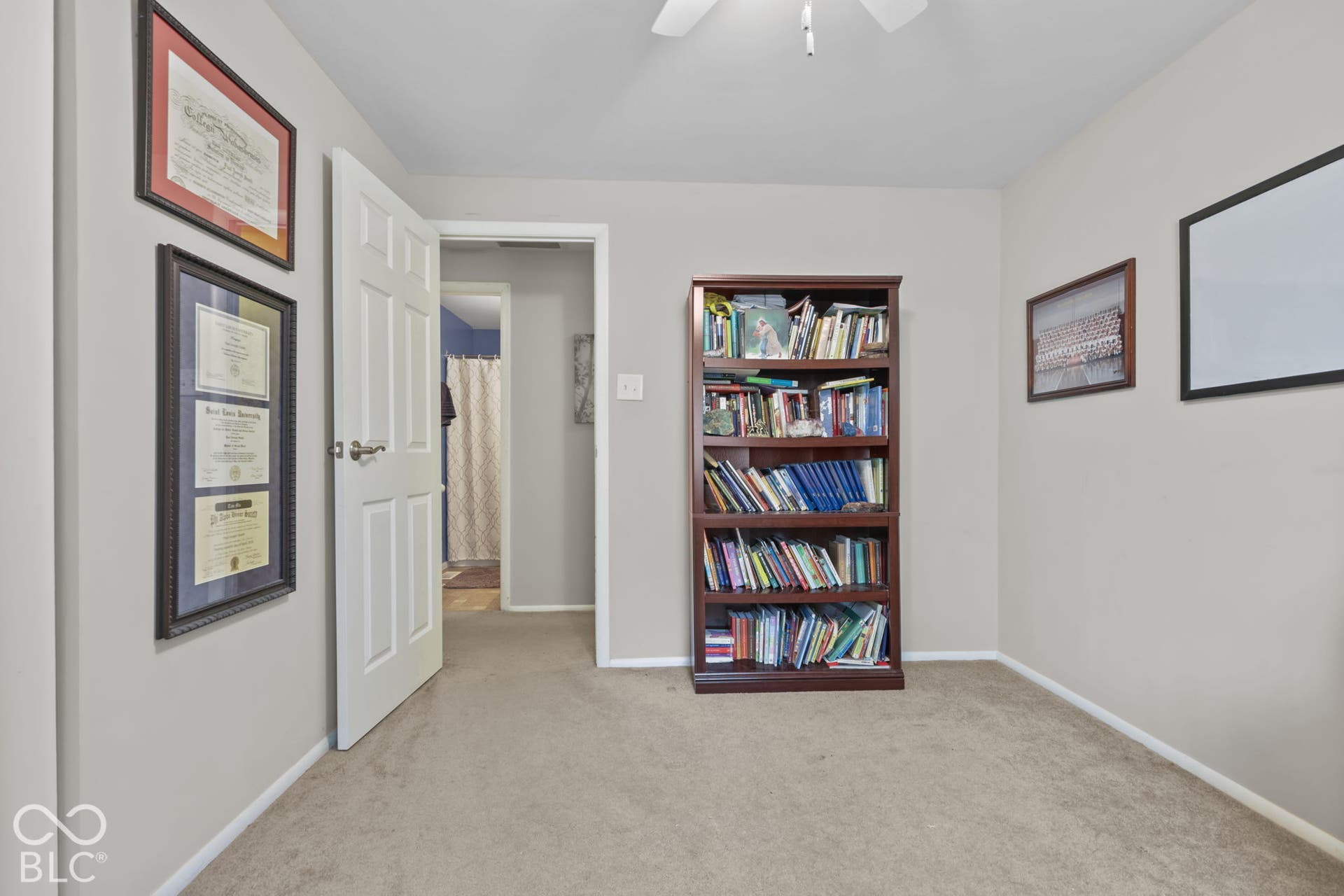Neutral-toned room featuring neutral carpeting, a six-panel door, and a ceiling fan with light fixture