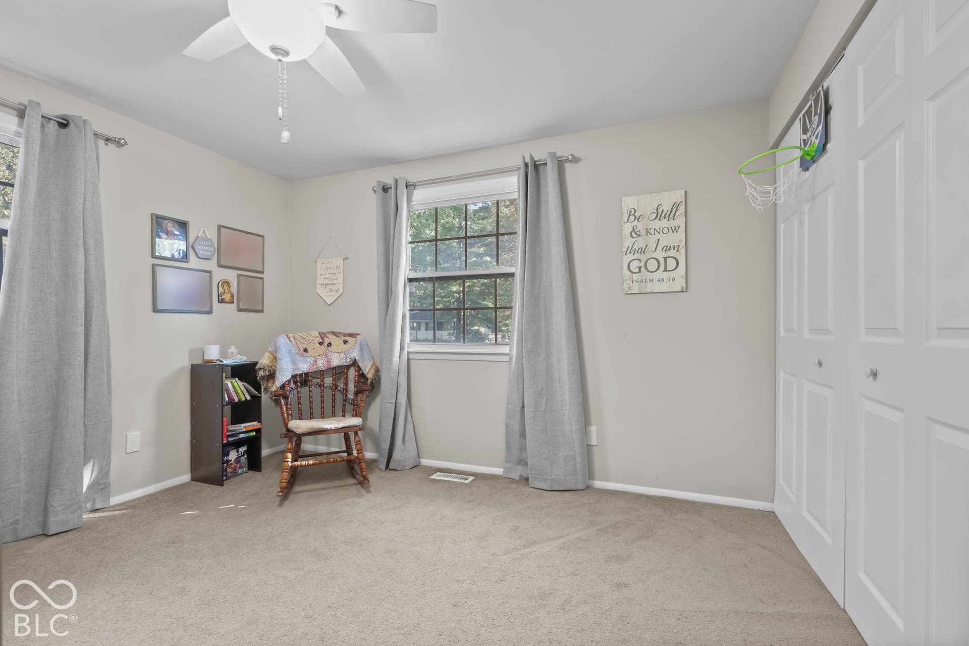 Neutral-toned interior featuring wall-to-wall carpeting, dual-pane windows, a ceiling fan with integrated lighting, and a double-door closet