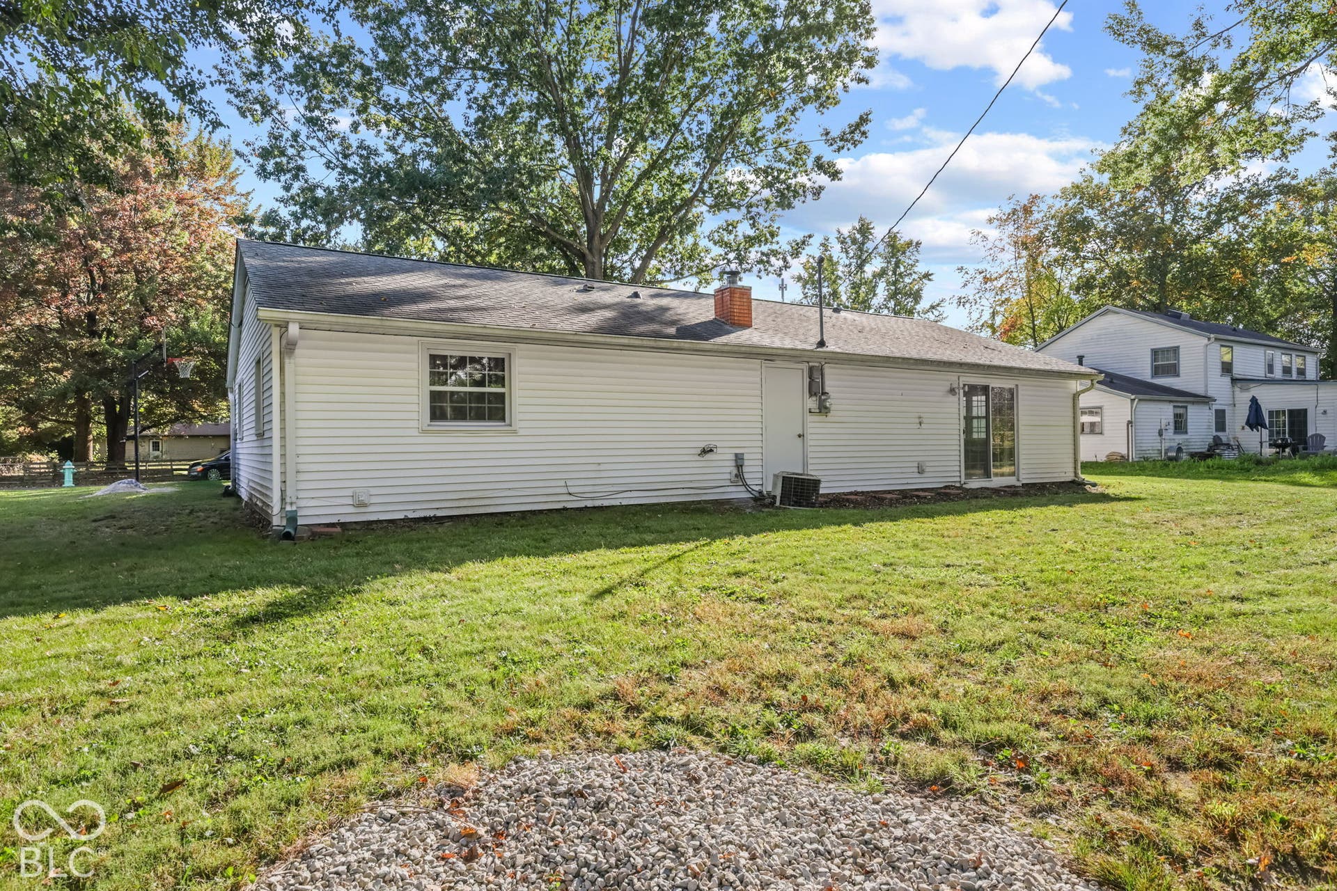 Ranch-style exterior featuring white vinyl siding, a shingled roof, a brick chimney, and a sliding glass door