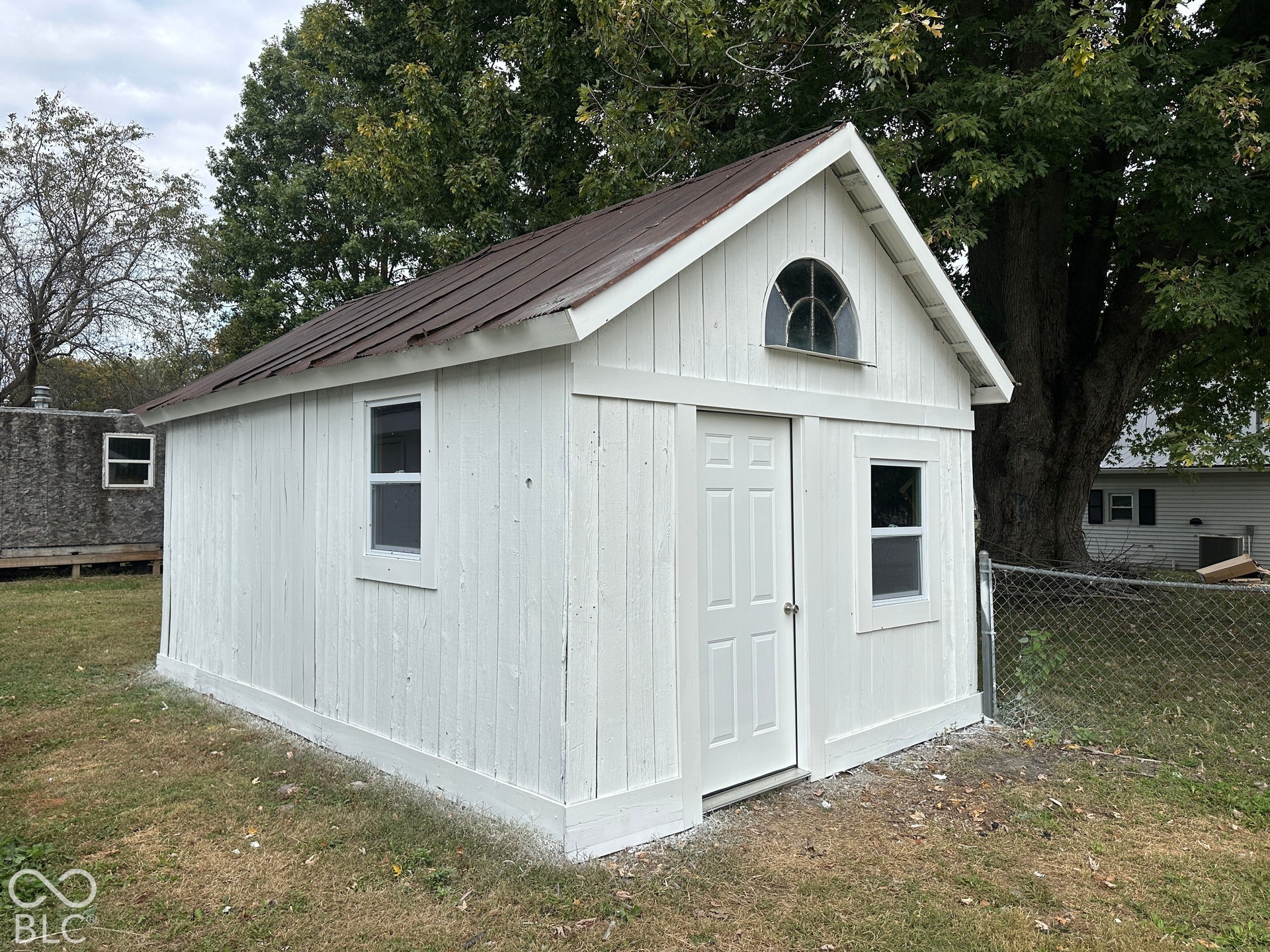 White-painted outbuilding with a brown metal roof