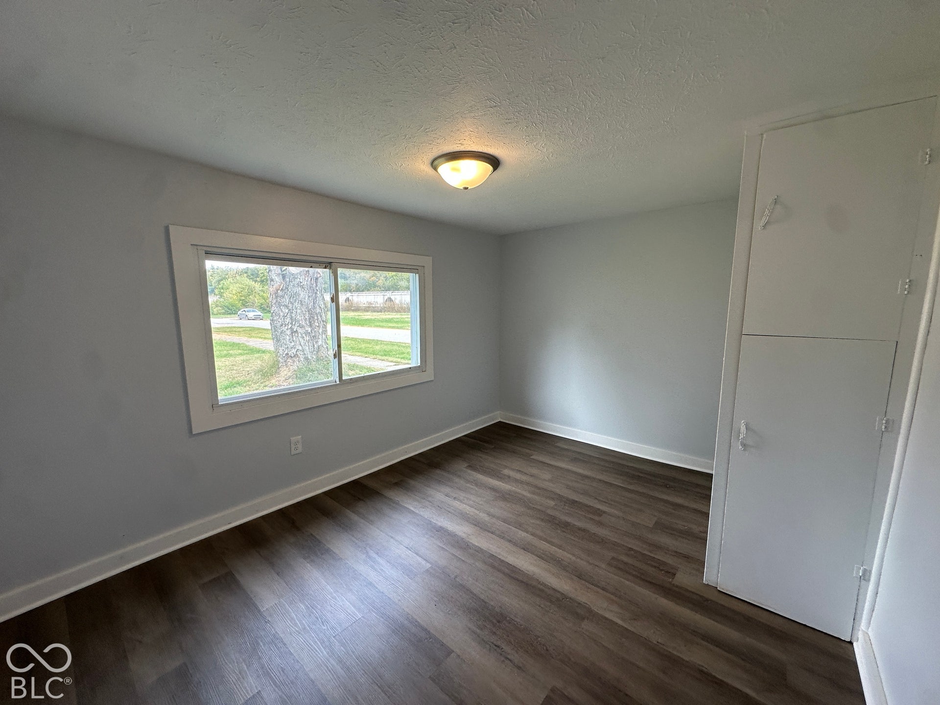 Wood-finish flooring, light gray walls, built-in storage cabinet, white trim, and overhead lighting