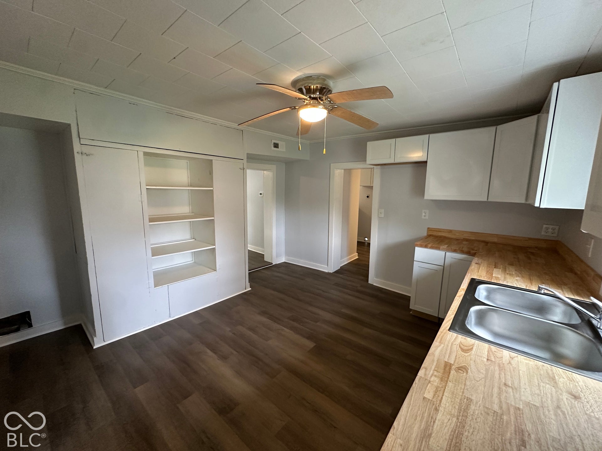 Wood-finish flooring throughout, with a ceiling fan light fixture and recessed shelving