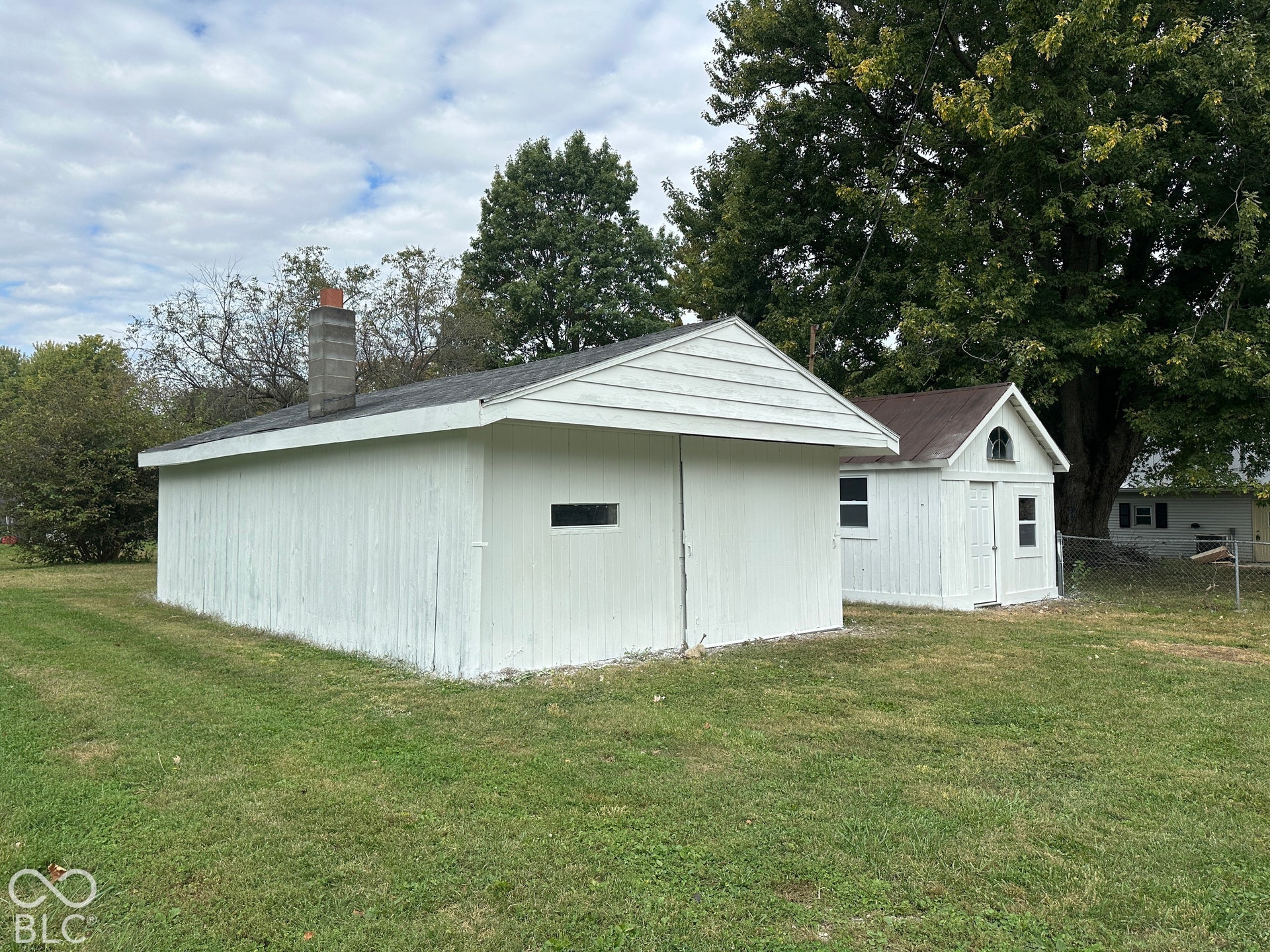 Two white-painted outbuildings with shingle roofs