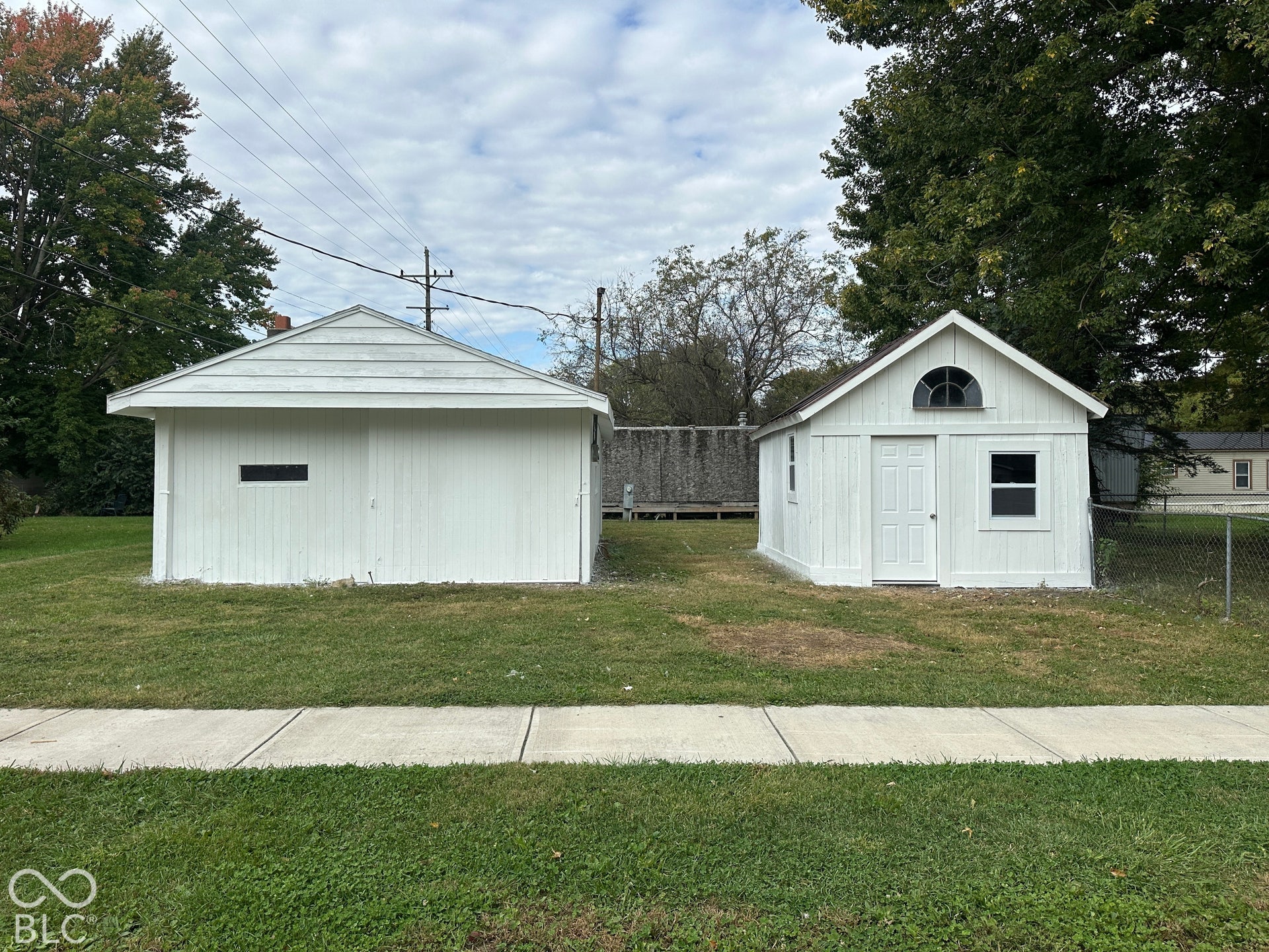 Two detached utility structures with white siding