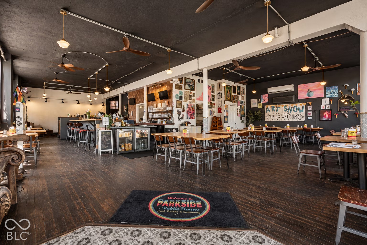 2602 Shelby Street, Indianapolis, IN 46203 Virtually Altered - Open-concept interior featuring dark-stained wood flooring, high exposed ceilings with industrial-style light fixtures, and a built-in service bar area