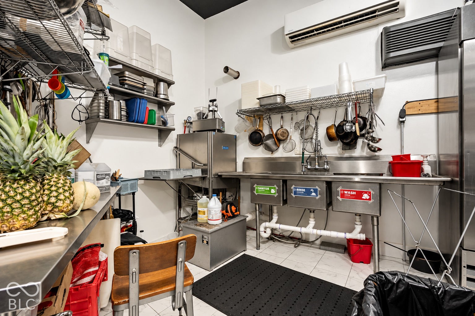 2602 Shelby Street, Indianapolis, IN 46203 Virtually Altered - Commercial-grade stainless steel three-compartment sink, mounted wire shelving units, stainless steel prep surfaces, and wall-mounted climate control system