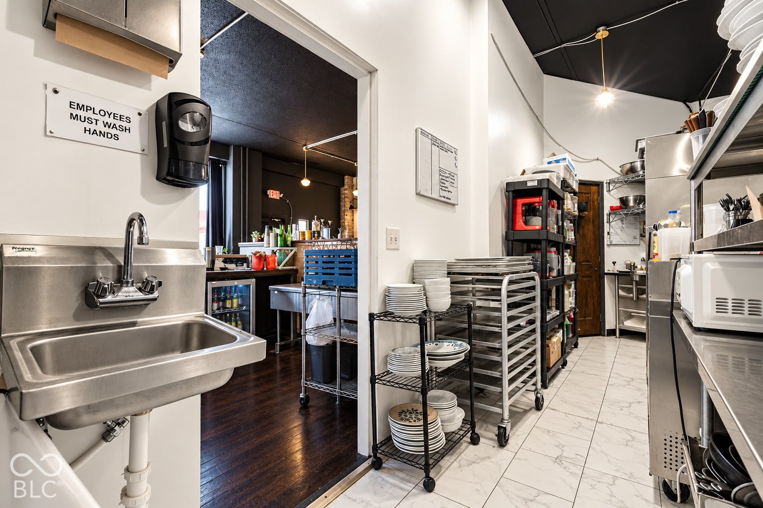 2602 Shelby Street, Indianapolis, IN 46203 Virtually Altered - Commercial kitchen space featuring stainless steel basin with wall-mounted faucet, tile flooring, and dark-toned ceiling finish