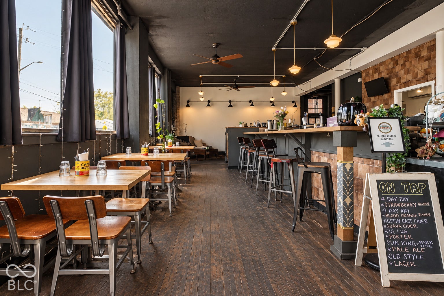 2602 Shelby Street, Indianapolis, IN 46203 Virtually Altered - Commercial space featuring wood-finish flooring, a built-in bar with decorative tile accents, exposed track lighting, and expansive windows