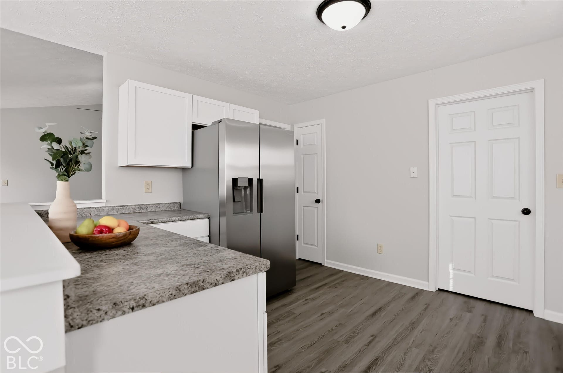 Kitchen featuring white cabinetry, stone-finish countertops, stainless steel side-by-side refrigerator, and wood-finish flooring