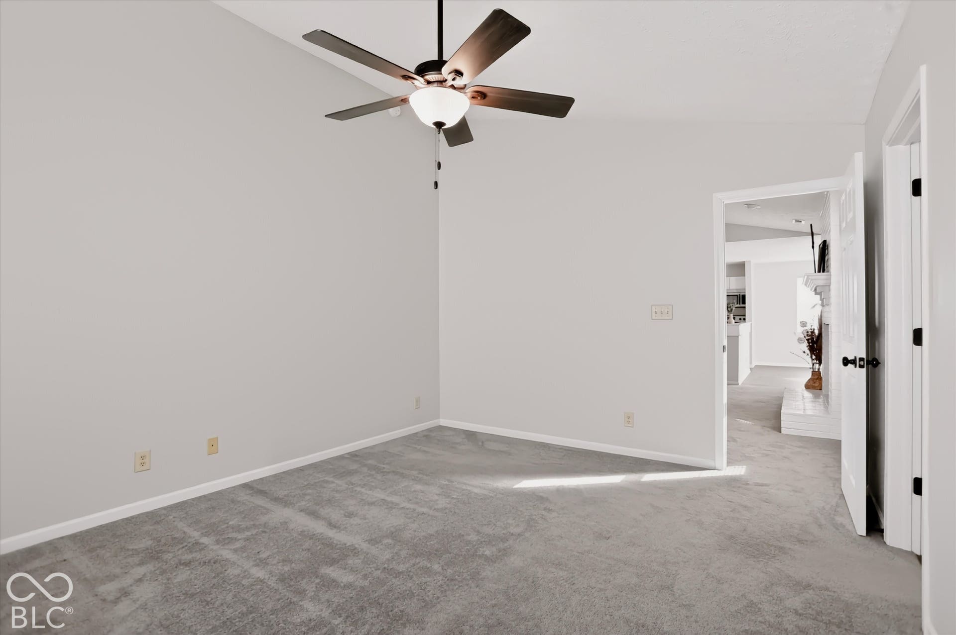Vaulted ceilings, neutral wall color, carpeted flooring, and a central ceiling fan with integrated lighting
