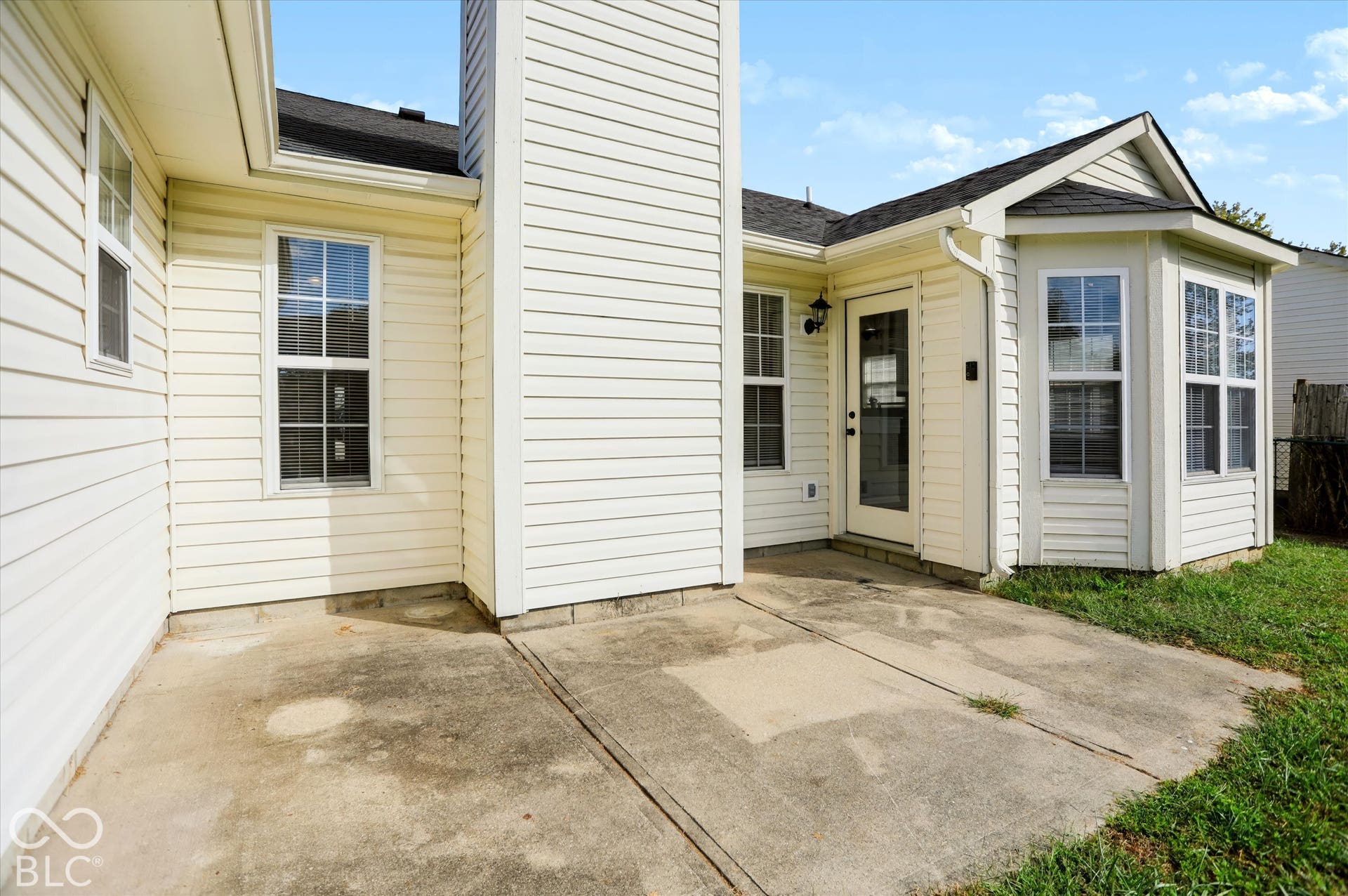 Exterior patio featuring light-colored horizontal siding, a prominent chimney, and a bay window configuration