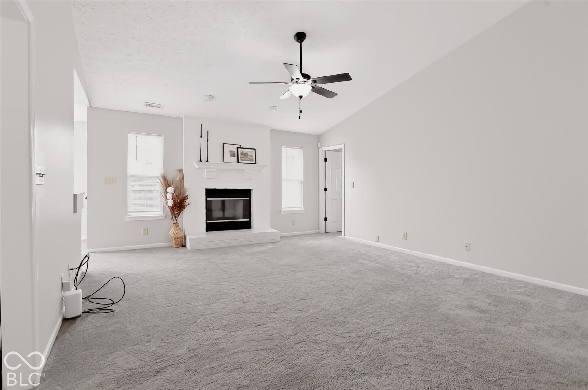 Vaulted ceilings, carpeted flooring, and a fireplace with a white mantel