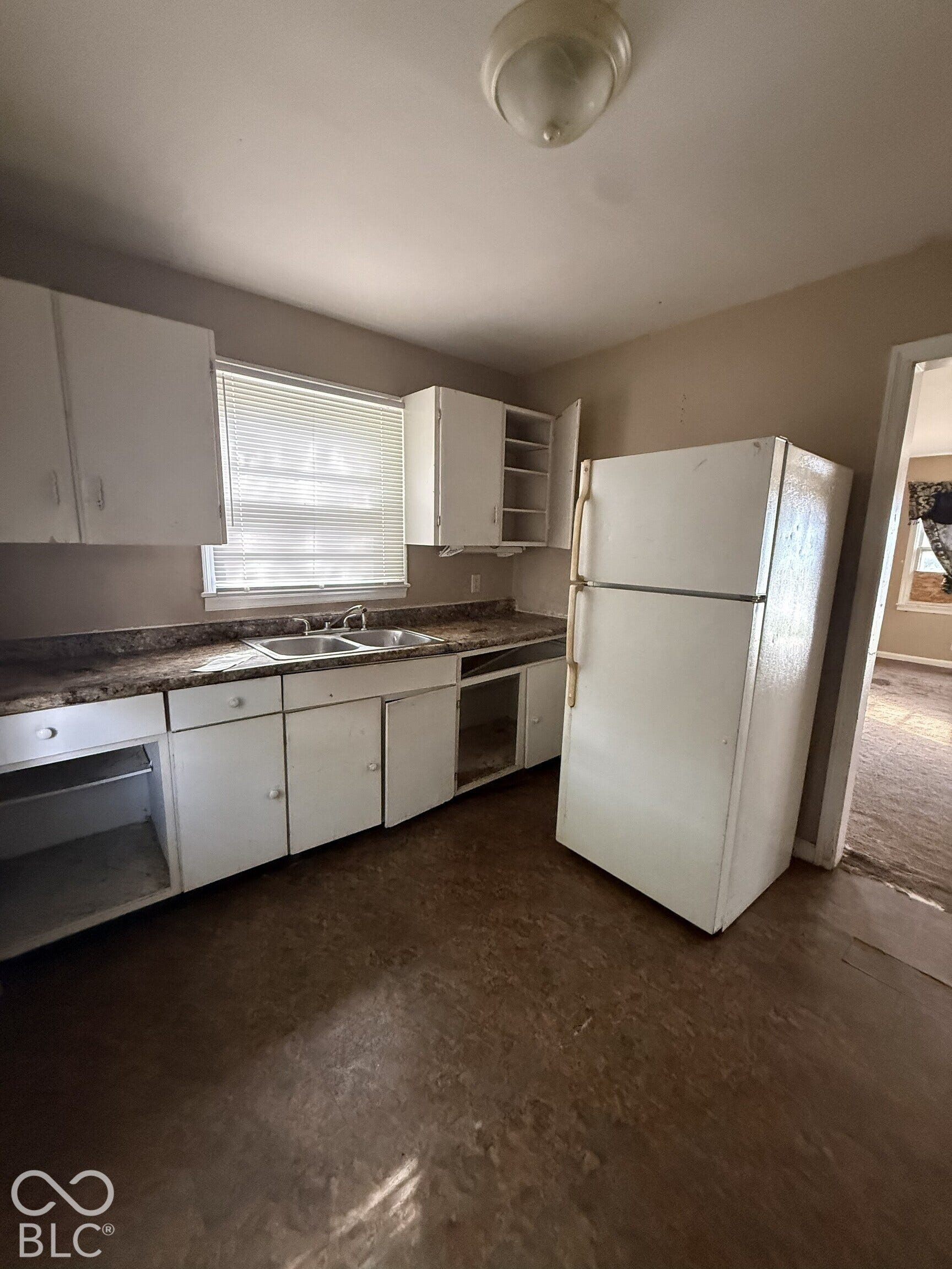 3351 N Grant Avenue, Indianapolis, IN 46218 Kitchen featuring white cabinetry, solid-surface countertops, dual-basin sink, and integrated refrigerator