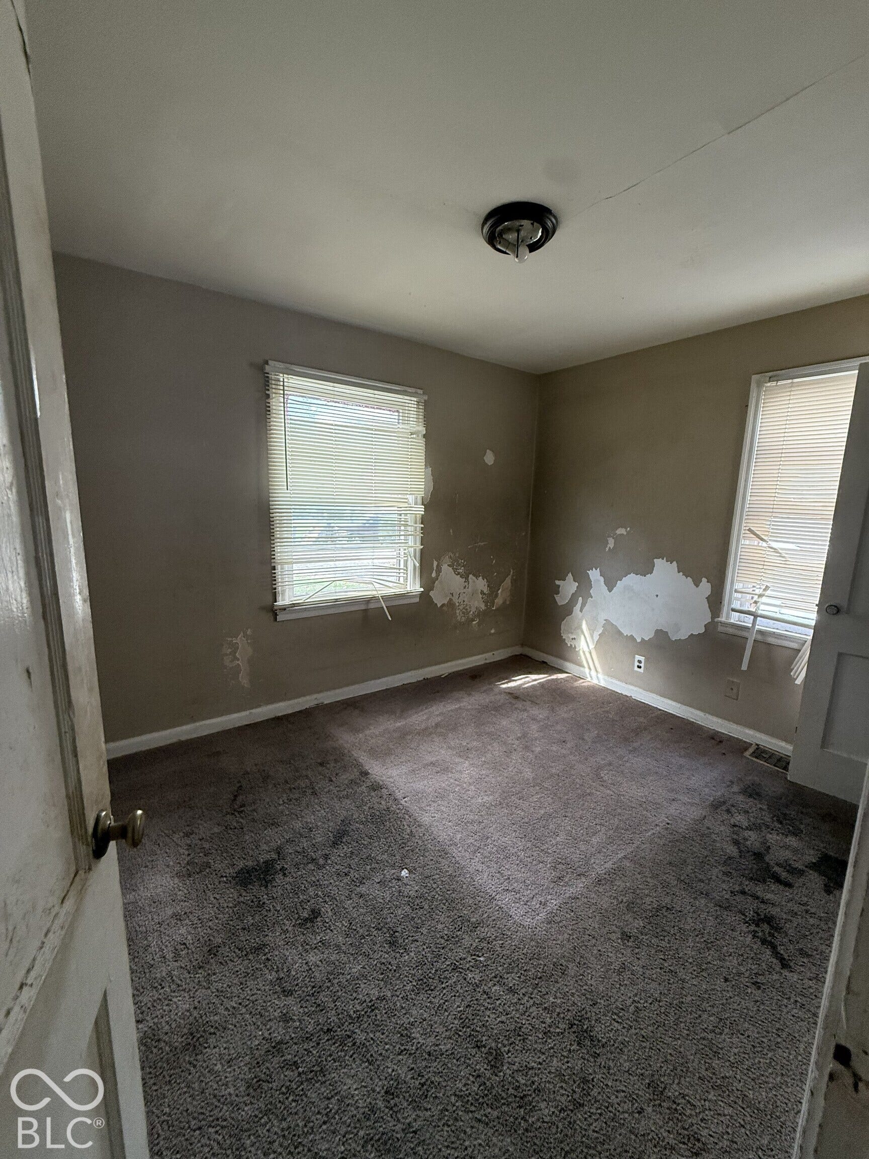 3351 N Grant Avenue, Indianapolis, IN 46218 Room featuring two windows, neutral carpeting, and a flush-mount ceiling light fixture