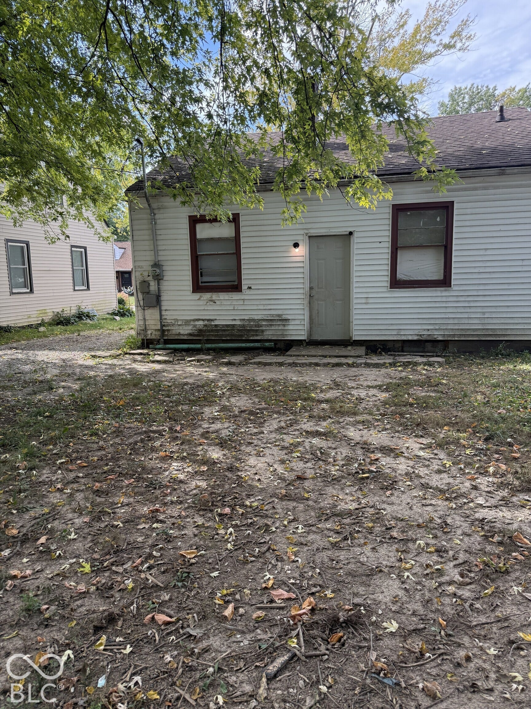 3351 N Grant Avenue, Indianapolis, IN 46218 Siding exterior featuring two windows with trim and a paved concrete landing