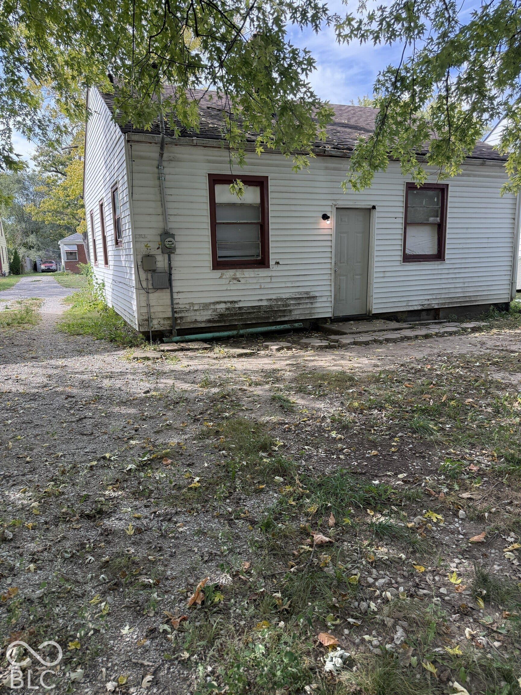 3351 N Grant Avenue, Indianapolis, IN 46218 Single-story exterior featuring white vinyl siding, a pitched roof, and a gravel driveway