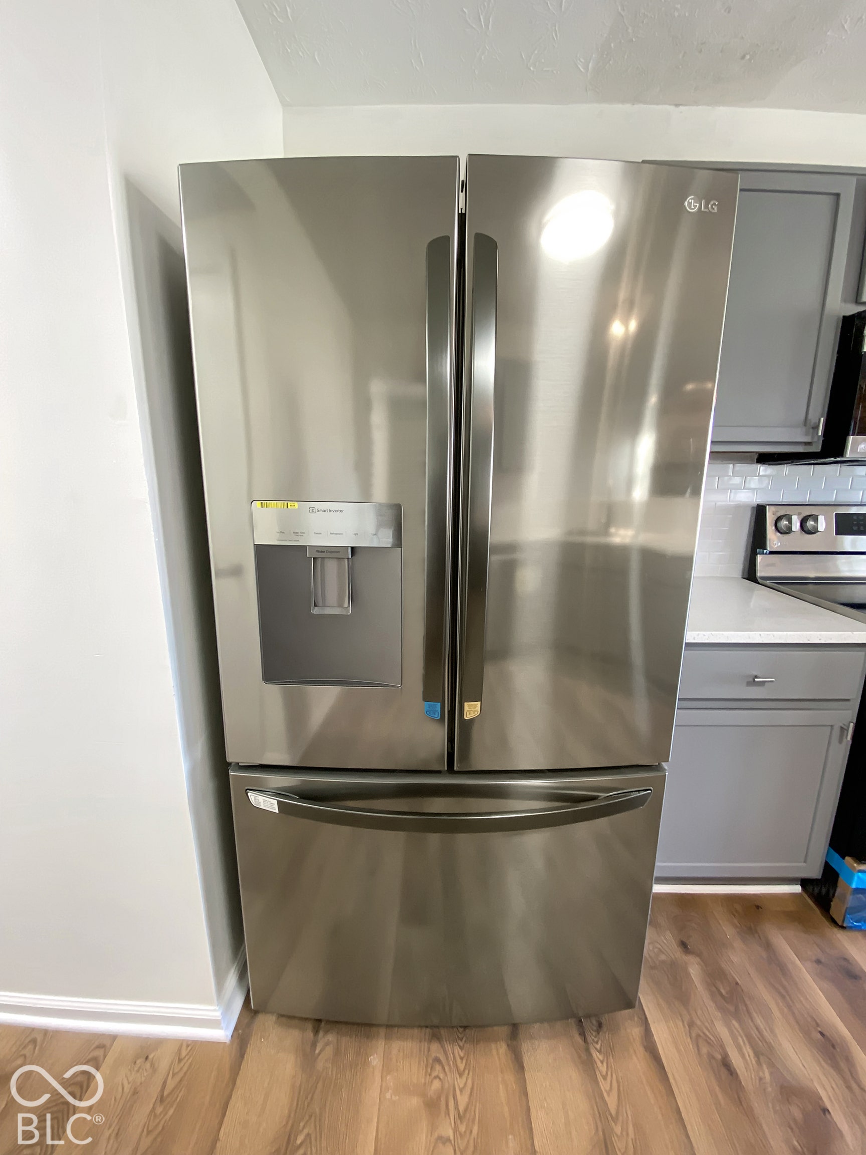 4726 Eva Court, Indianapolis, IN 46227 Stainless steel French door refrigerator with an integrated water and ice dispenser, paired with grey shaker-style cabinetry, white countertops, and wood-finish flooring