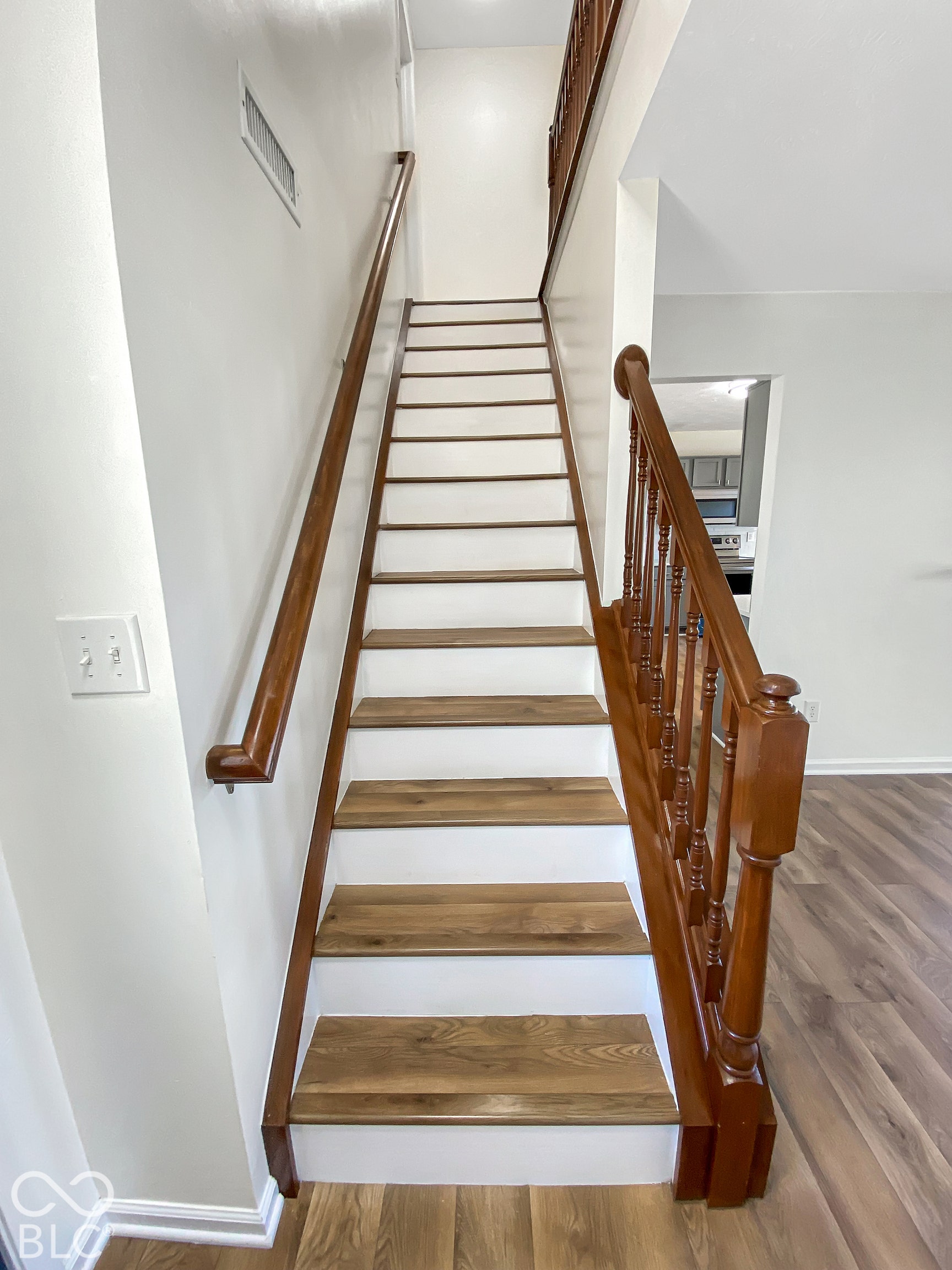 4726 Eva Court, Indianapolis, IN 46227 Staircase featuring wood-finish treads, white risers, a stained wood handrail, and traditional wood balusters