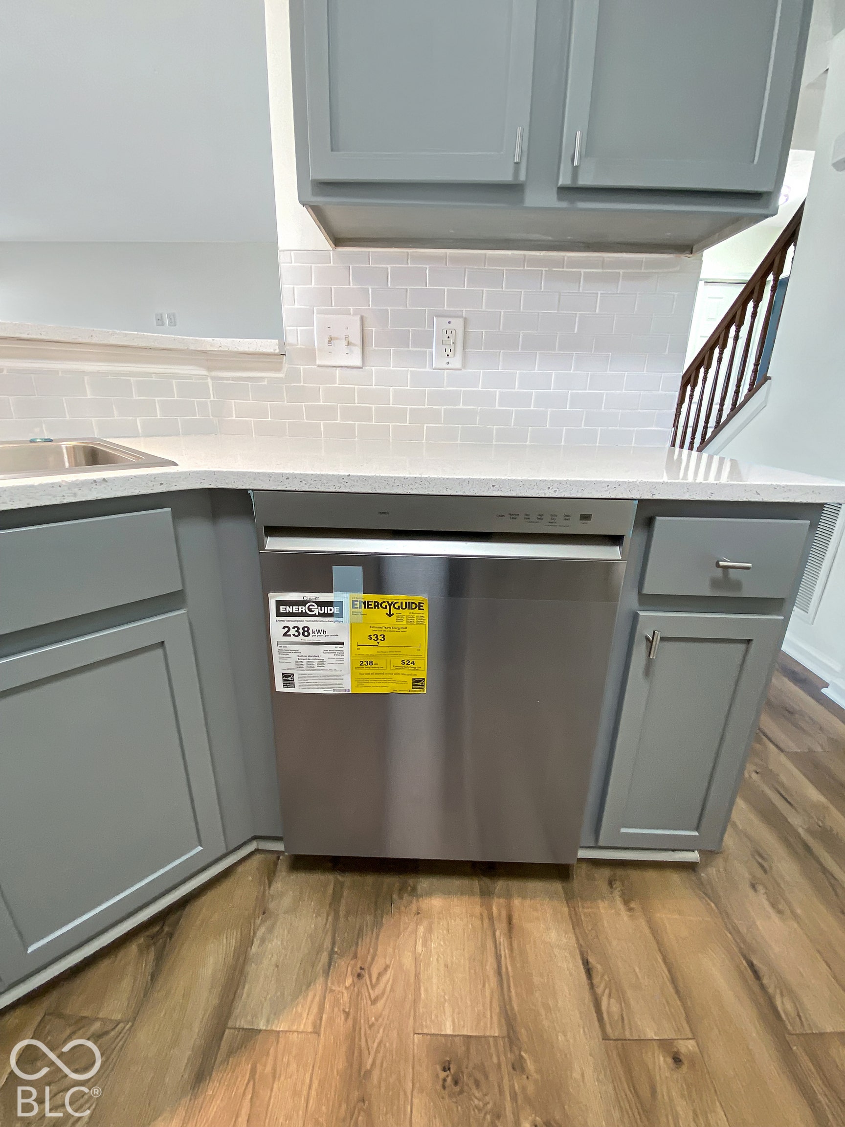 4726 Eva Court, Indianapolis, IN 46227 Kitchen featuring grey shaker-style cabinetry, solid surface countertops, a white subway tile backsplash, stainless steel dishwasher, and wood-finish flooring