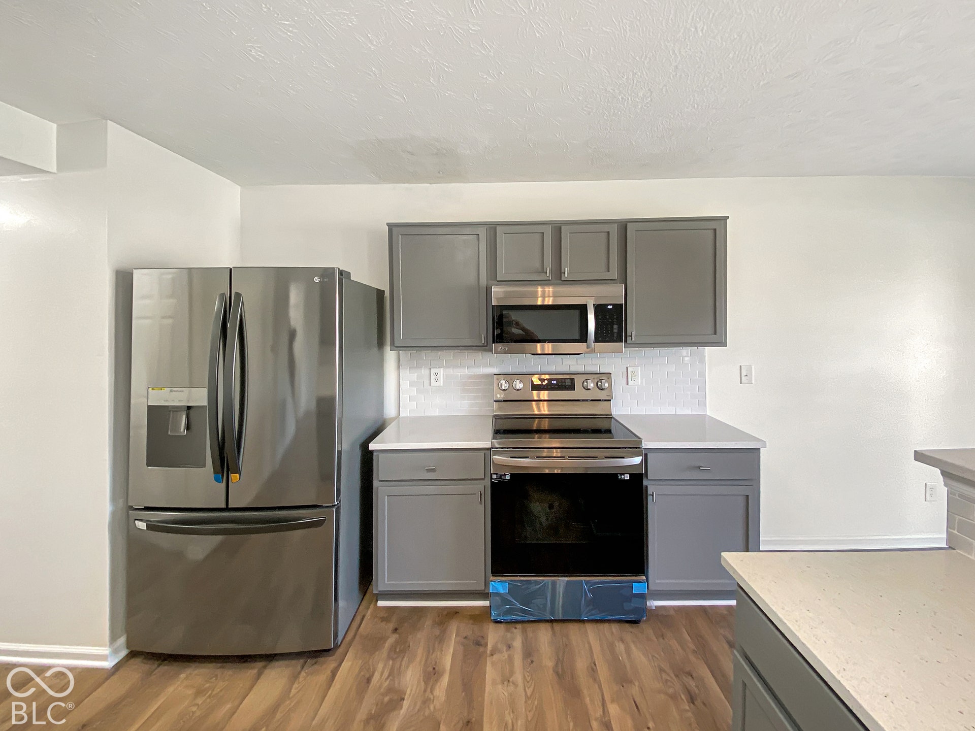 4726 Eva Court, Indianapolis, IN 46227 Kitchen featuring grey cabinetry, stainless steel appliances, quartz countertops, a tiled backsplash, and wood-finish flooring