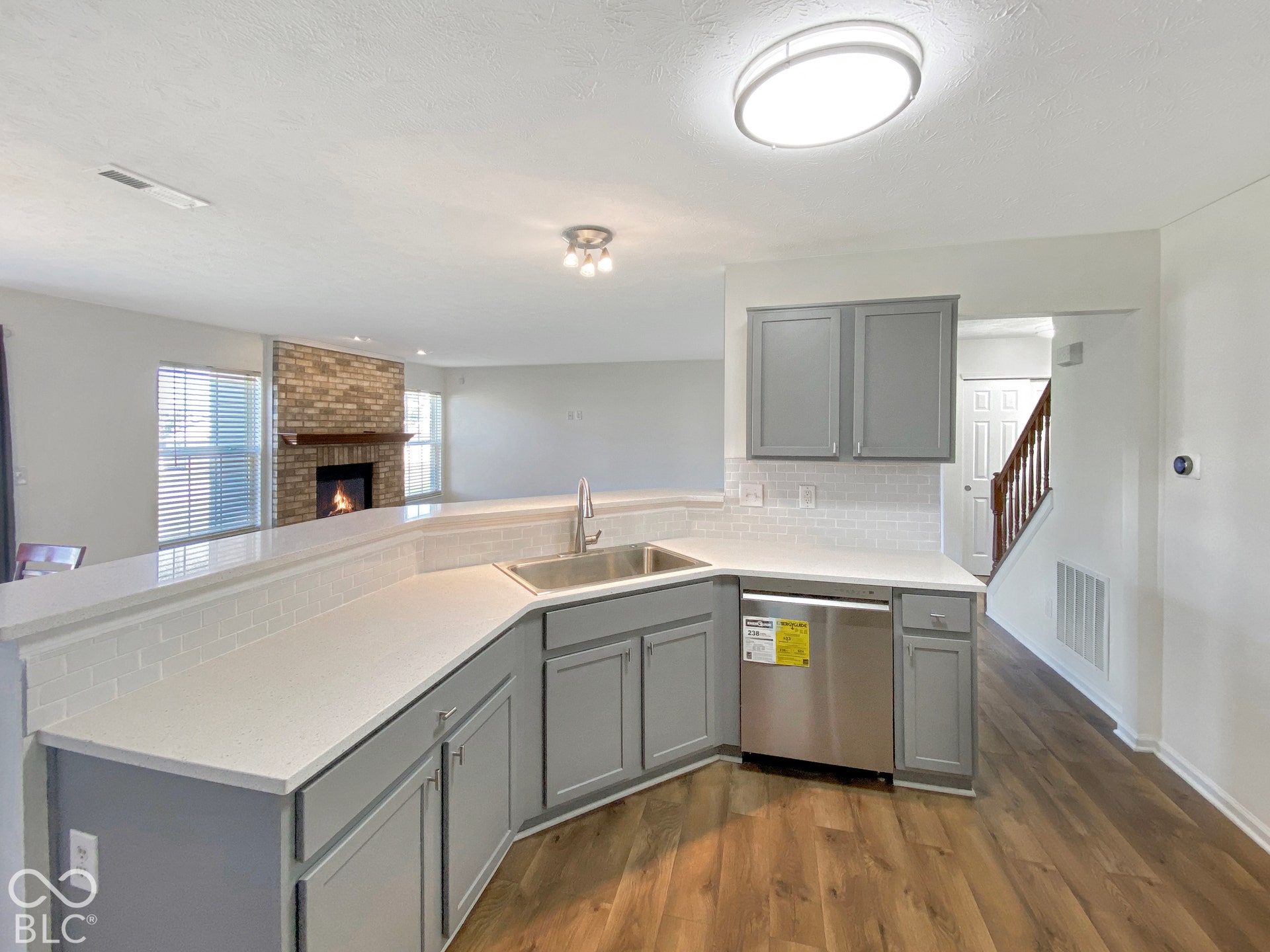 4726 Eva Court, Indianapolis, IN 46227 Kitchen featuring grey shaker-style cabinetry, white countertops, a stainless steel undermount sink, a white subway tile backsplash, and wood-finish flooring