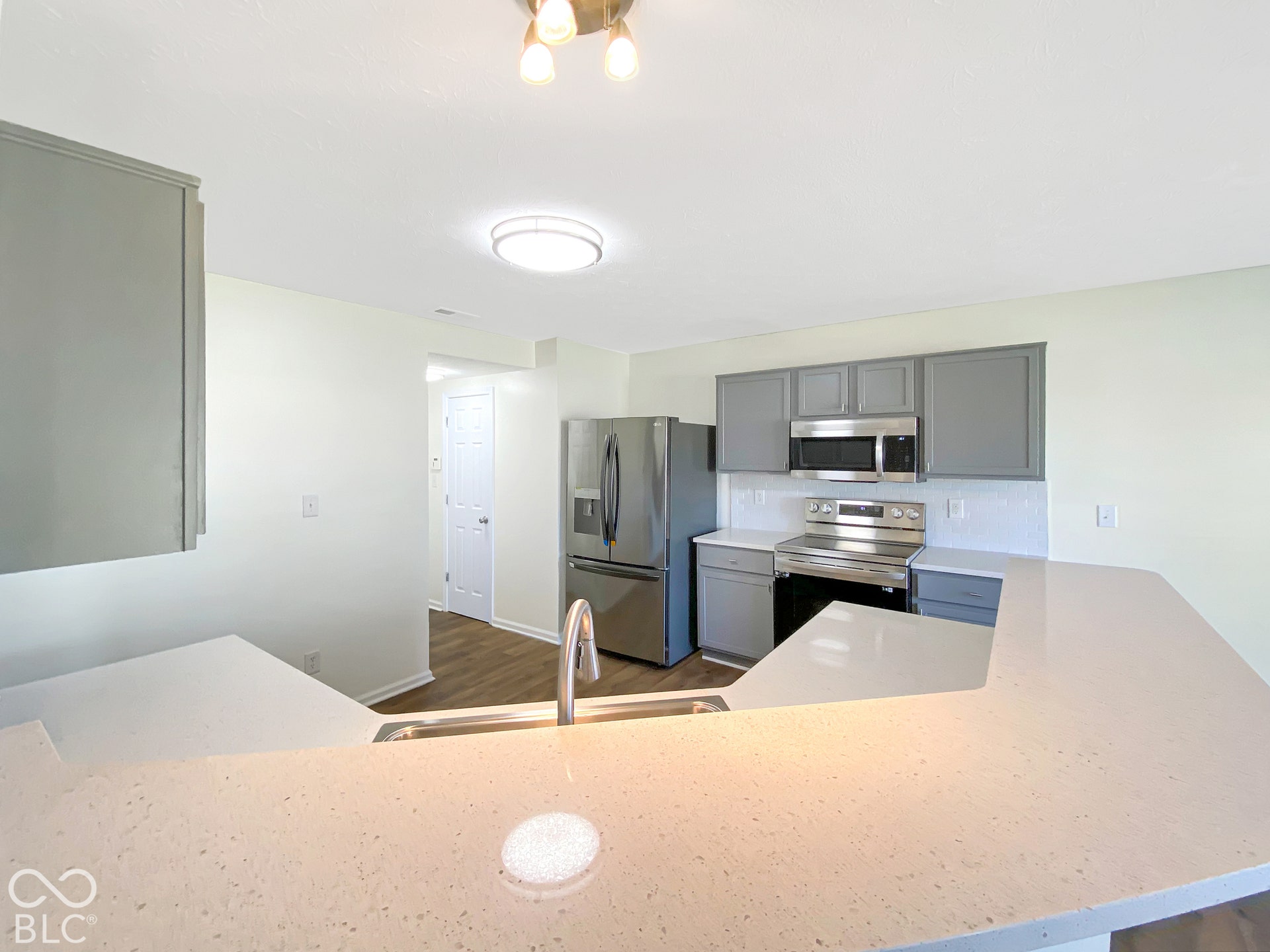 4726 Eva Court, Indianapolis, IN 46227 Kitchen featuring grey cabinetry, stainless steel appliances, quartz countertops, a peninsula, and wood-finish flooring