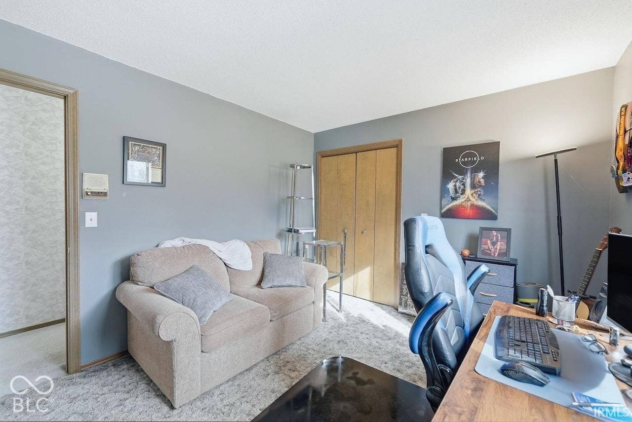 Interior room featuring neutral-toned carpeting, wood-finish closet doors, and light gray wall paint