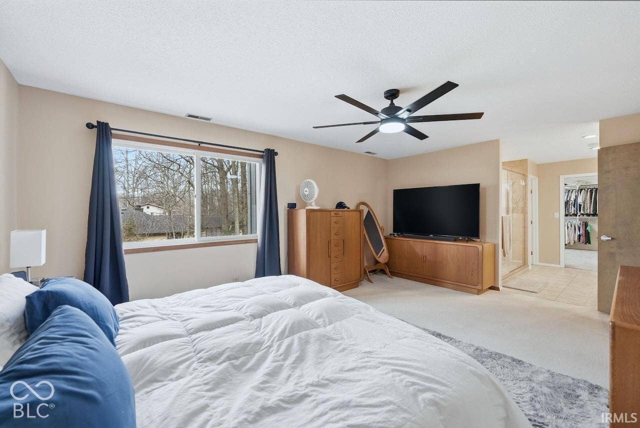 Bedroom featuring carpeting, a multi-blade ceiling fan with integrated lighting, and a large window