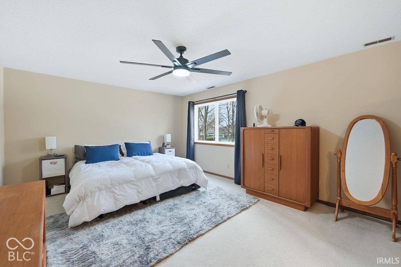 Neutral-toned room featuring a central ceiling fan with integrated lighting and a multi-pane window