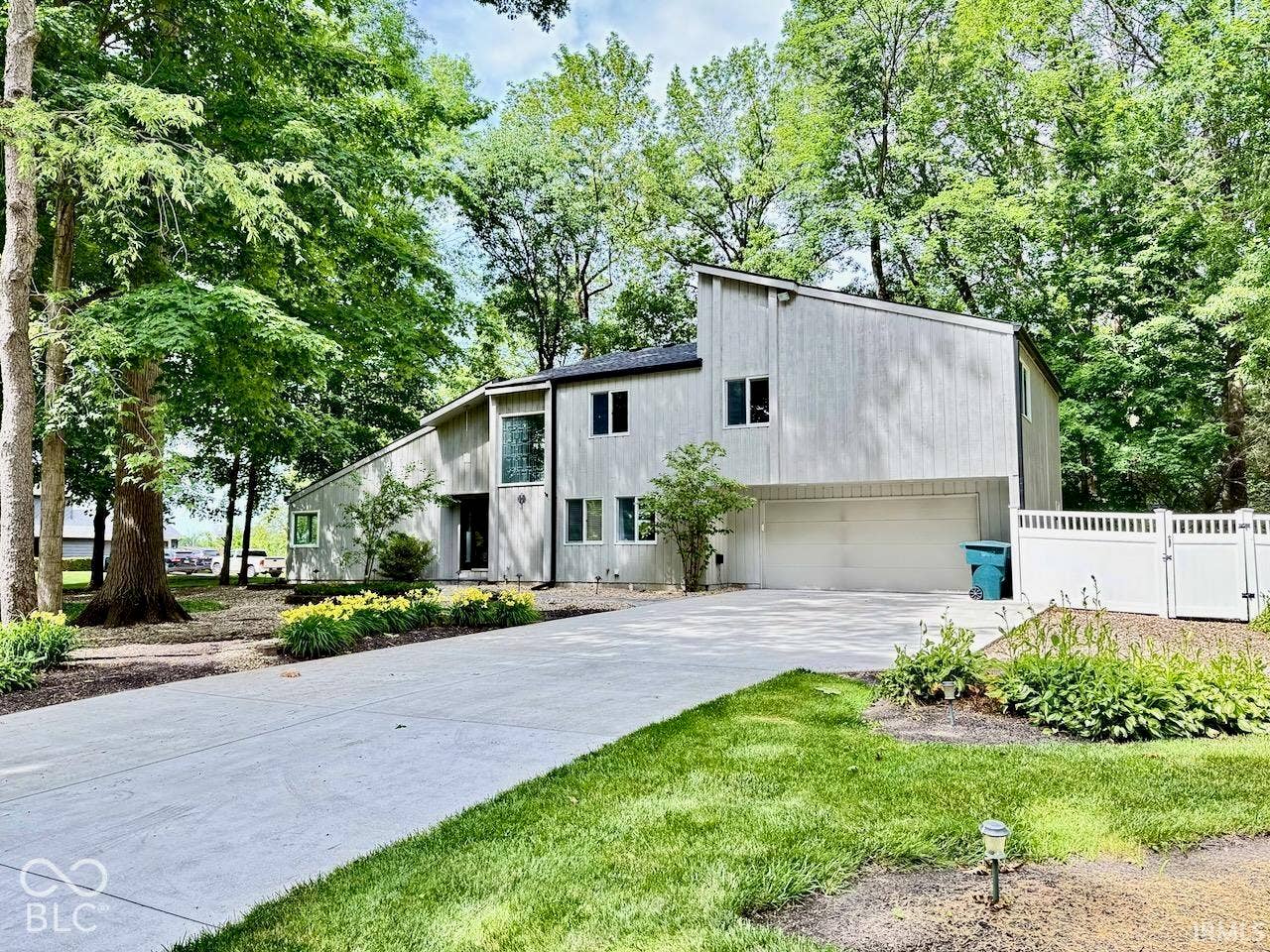 Contemporary exterior featuring vertical wood siding, shed roofline, attached multi-car garage, concrete driveway, and privacy fencing