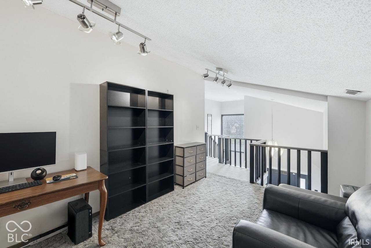Vaulted ceilings, track lighting fixtures, and metal railings overlooking the lower level