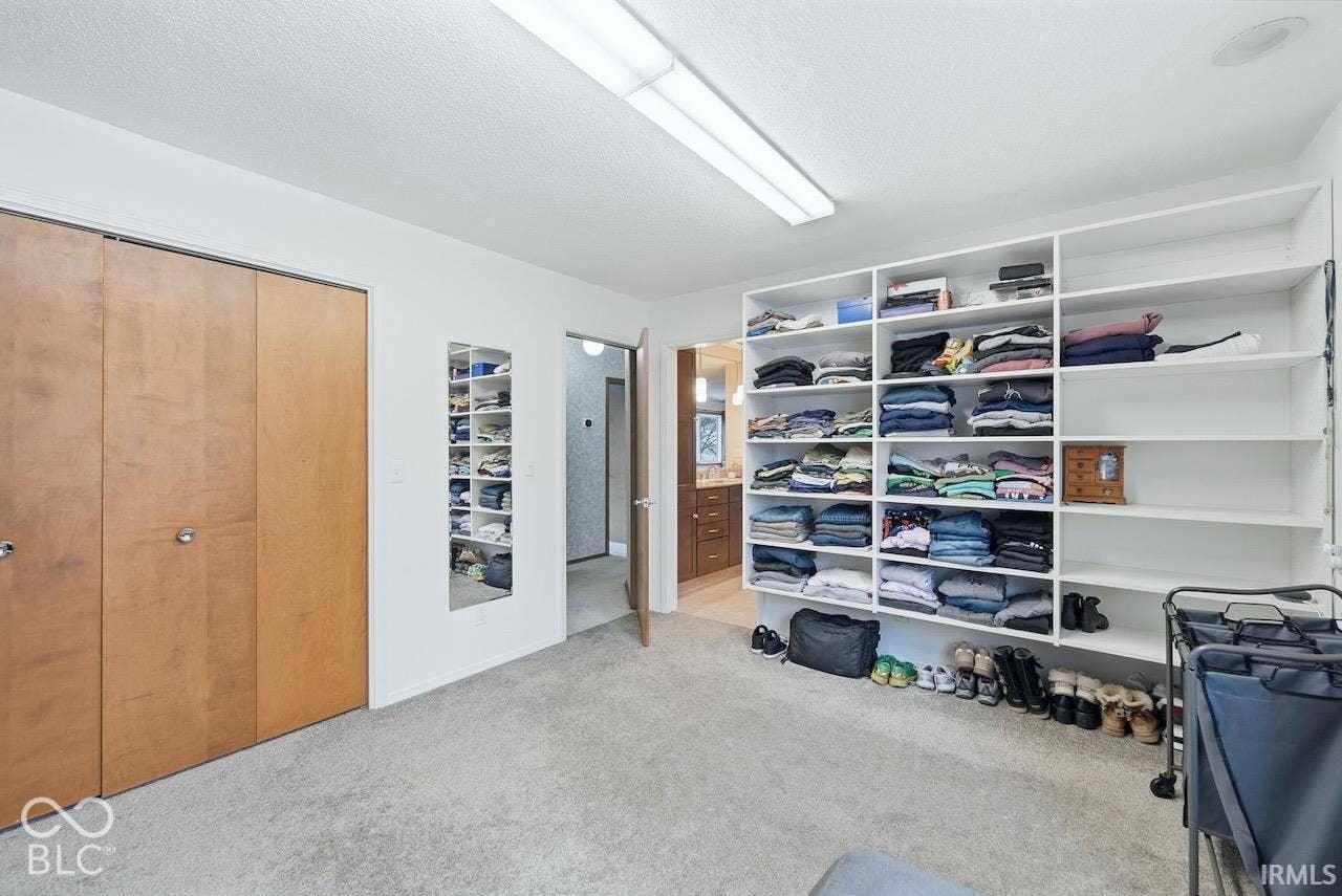 Built-in floor-to-ceiling white shelving, dual-panel wood-finish closet doors, and a wall-mounted full-length mirror