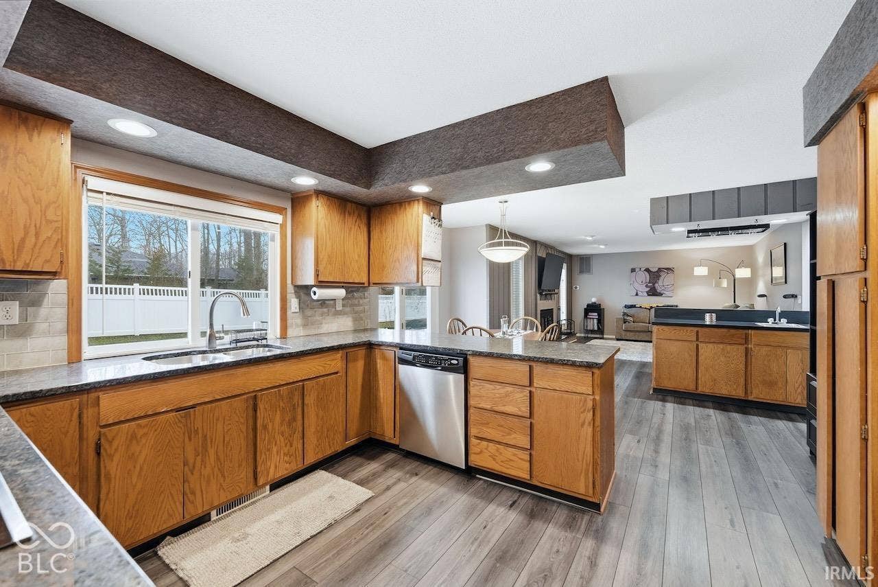 Kitchen featuring natural wood cabinetry, stone-finish countertops, stainless steel dishwasher, wood-finish flooring, and recessed lighting