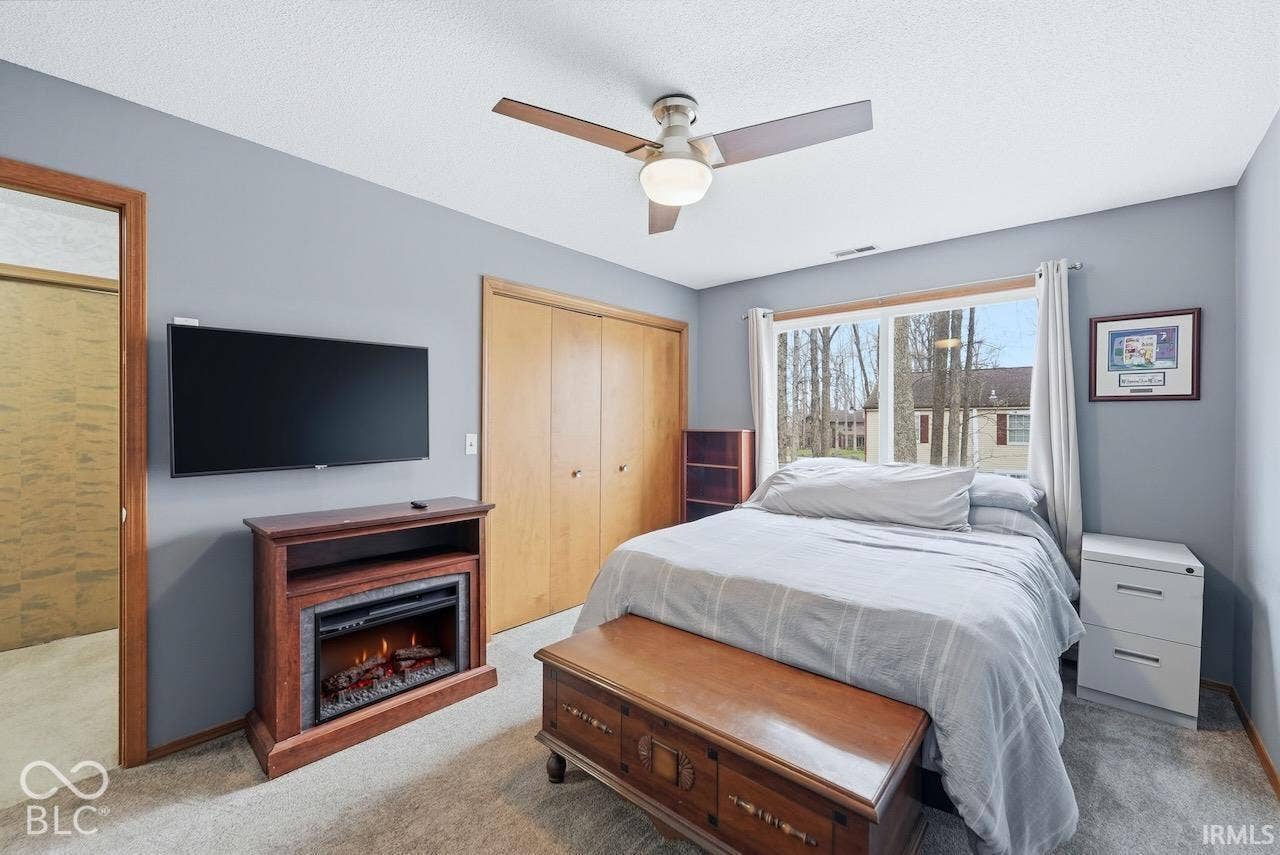 Neutral wall tones, ceiling fan with integrated lighting, dual-panel closet doors, and large picture window