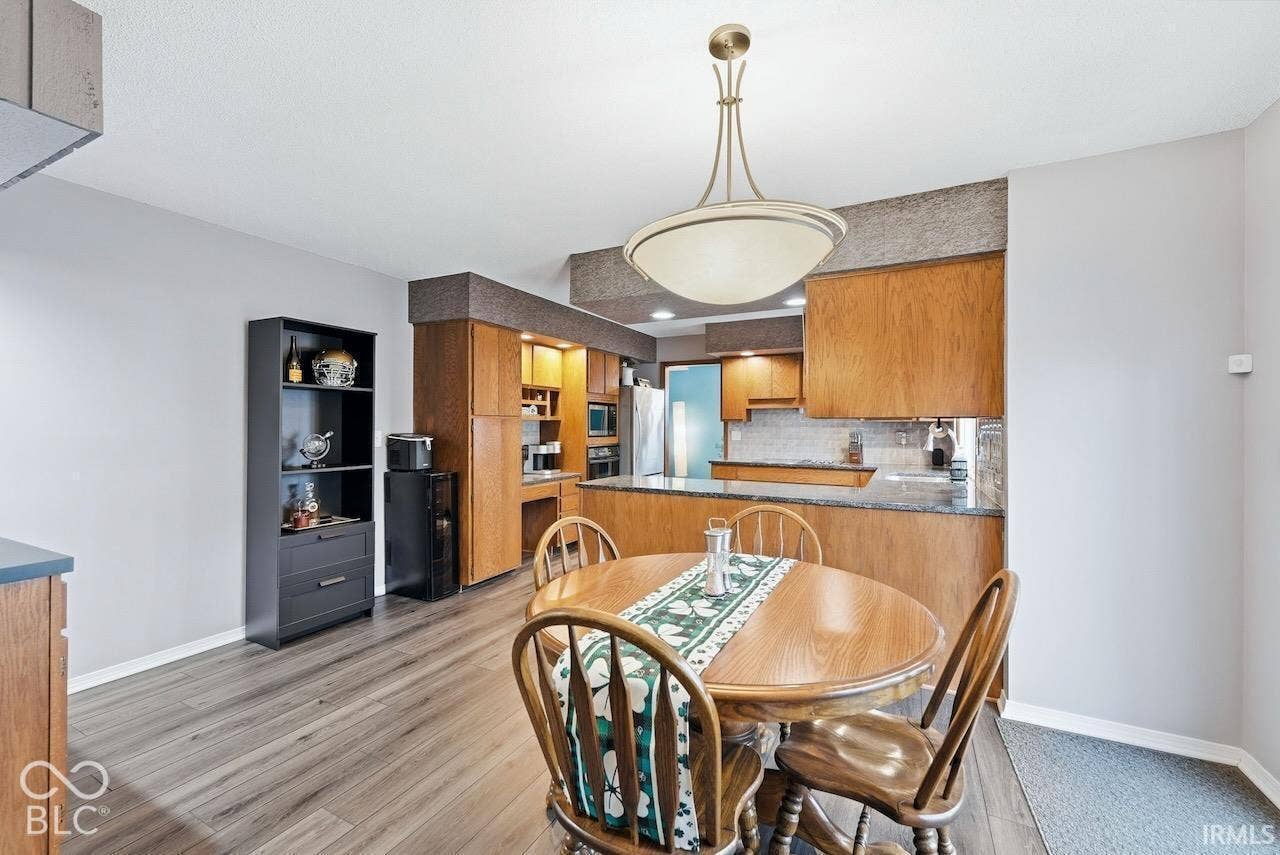 Kitchen area featuring wood-finish flooring, wood cabinetry, stone-finish countertops, and a modern pendant light fixture