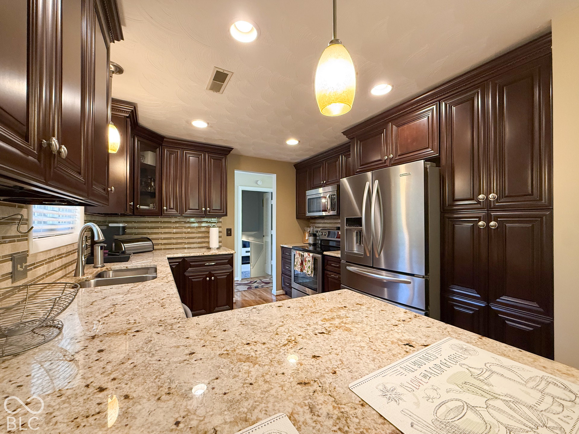 4225 Westbourne Drive, Indianapolis, IN 46205 Kitchen featuring dark wood cabinetry, light-toned stone countertops, horizontal tile backsplash, stainless steel appliances, and recessed lighting