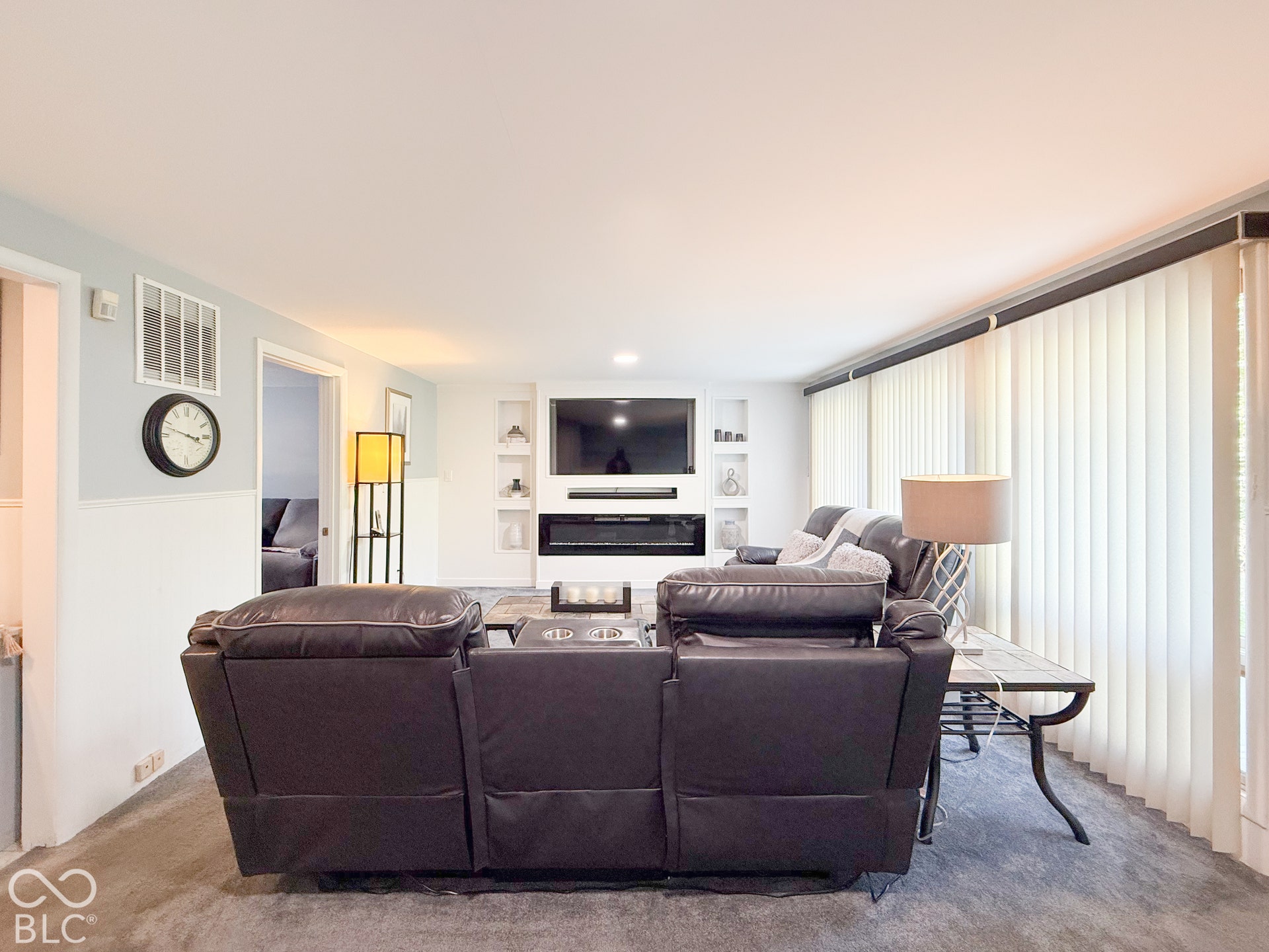 4225 Westbourne Drive, Indianapolis, IN 46205 Living area featuring a built-in electric fireplace, integrated shelving, vertical window blinds, and wainscoting