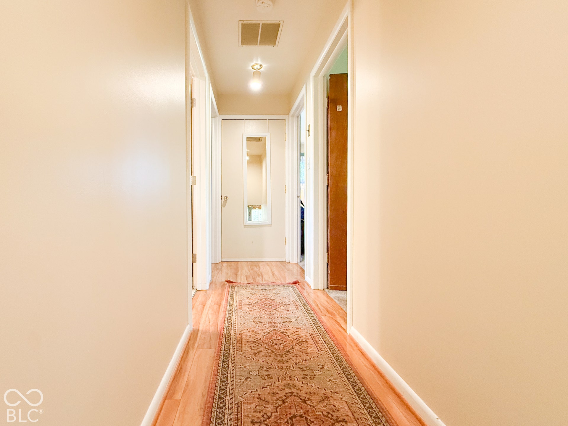 4225 Westbourne Drive, Indianapolis, IN 46205 Hallway featuring wood-finish flooring, neutral wall paint, and a door with a built-in mirror